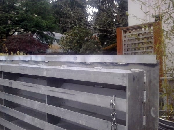 A metal fence with a wooden fence in the background