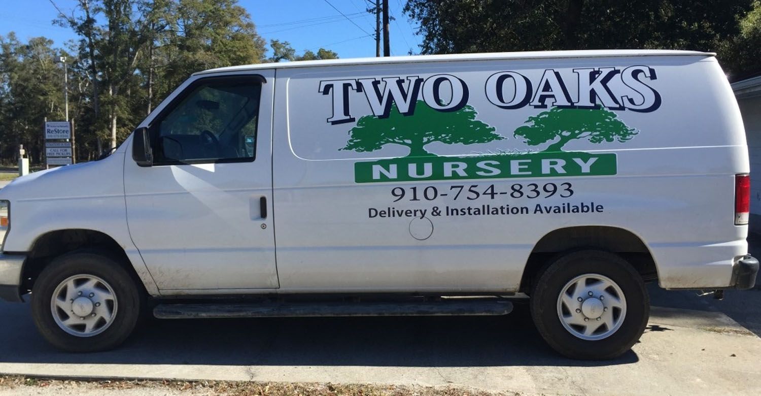 A white van for two oaks nursery is parked in a parking lot