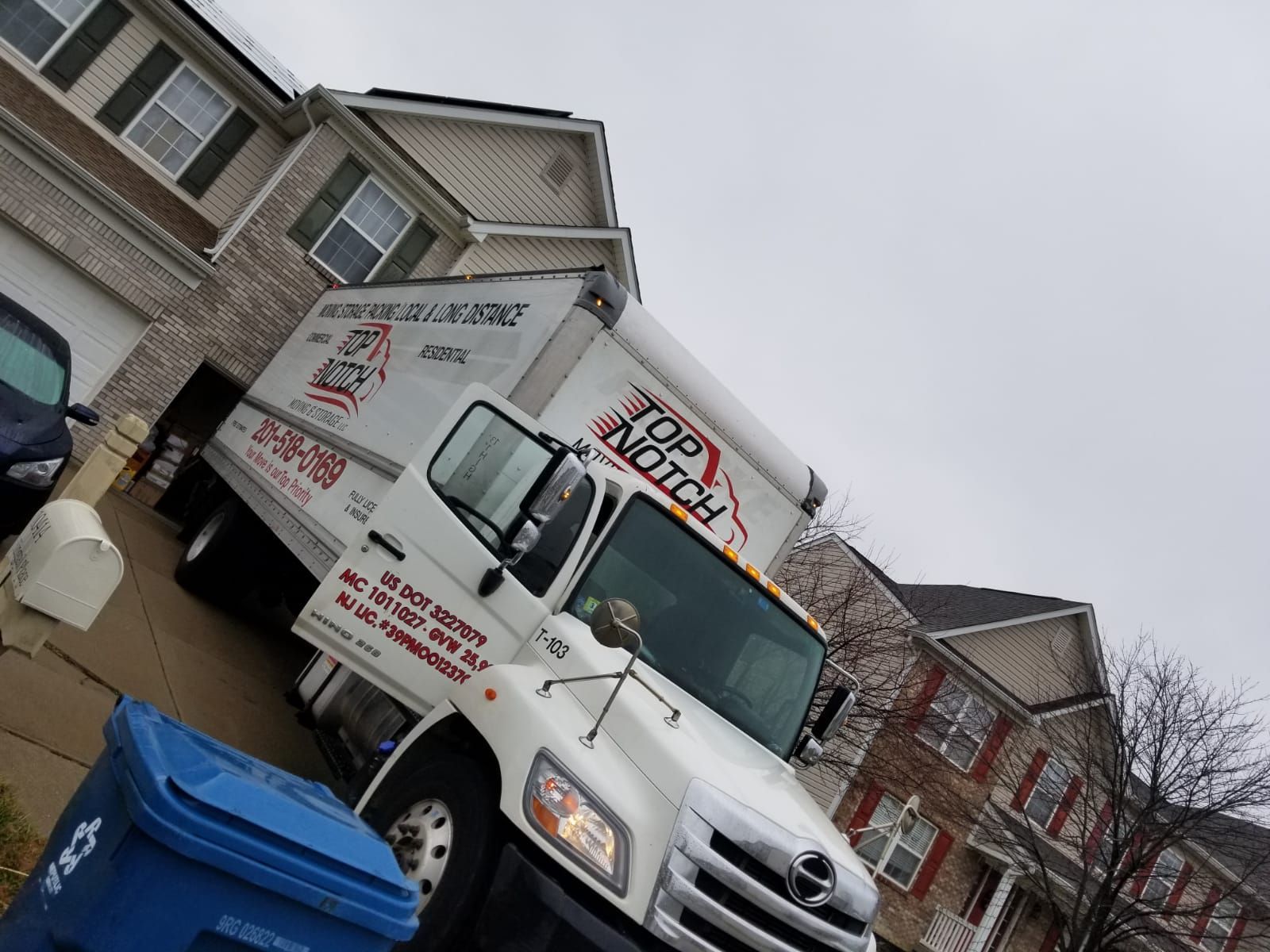 A white top notch truck is parked in front of a house