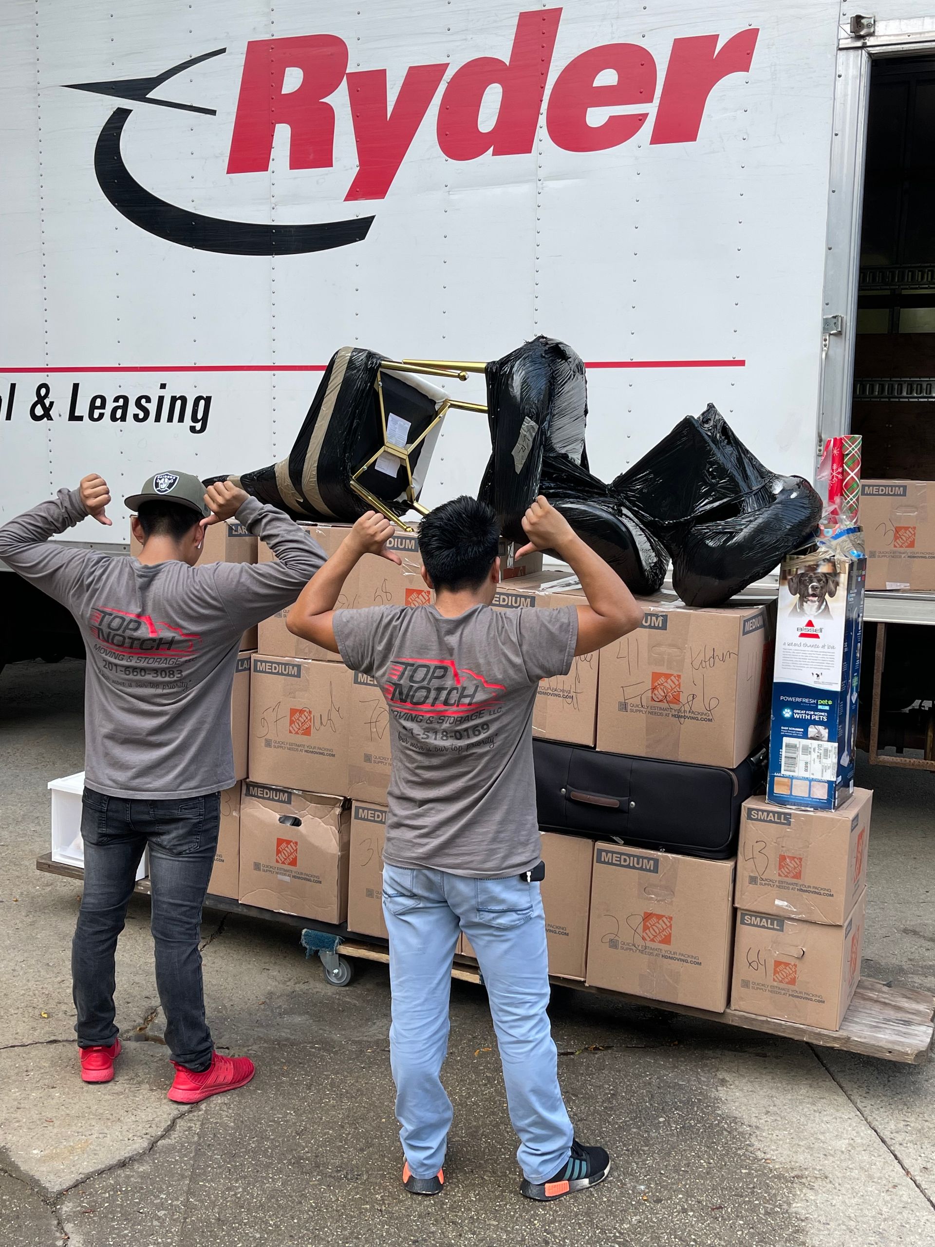 Two men are standing in front of a ryder truck.