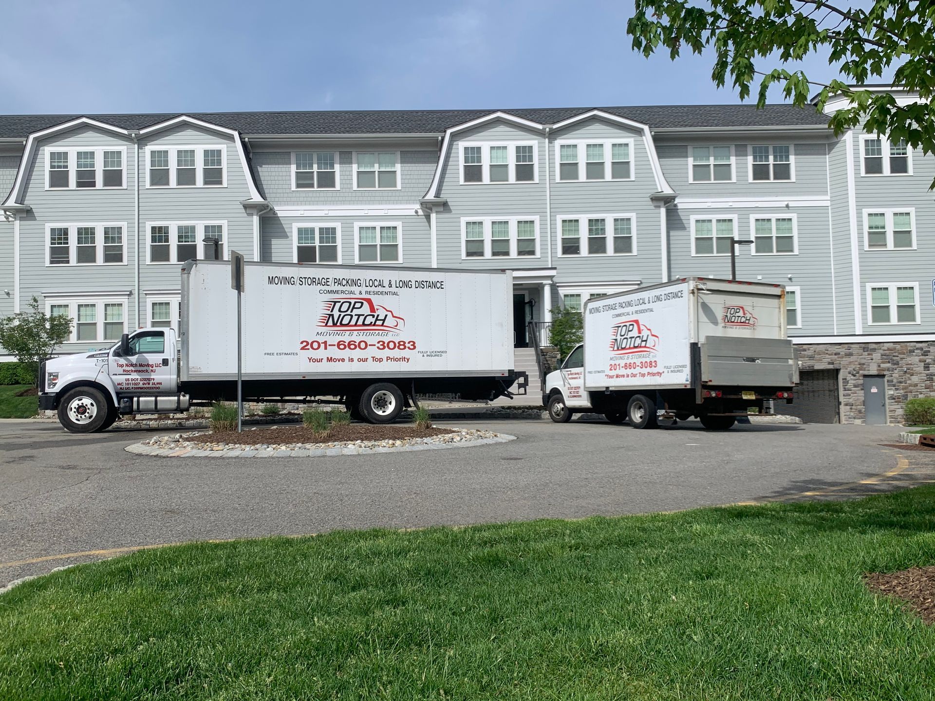 Two moving trucks are parked in front of a large building.