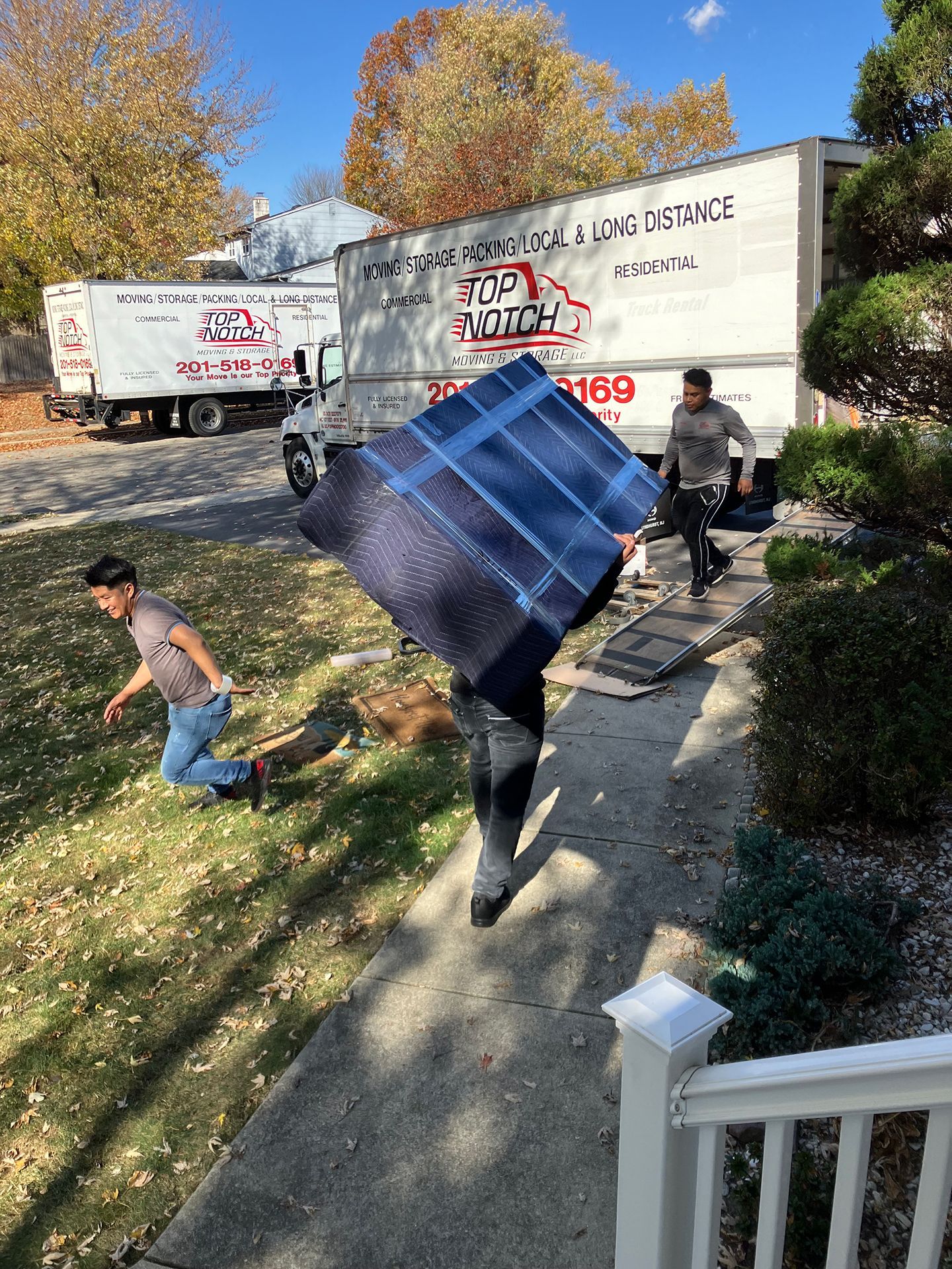 A man is carrying a large piece of furniture down a sidewalk.