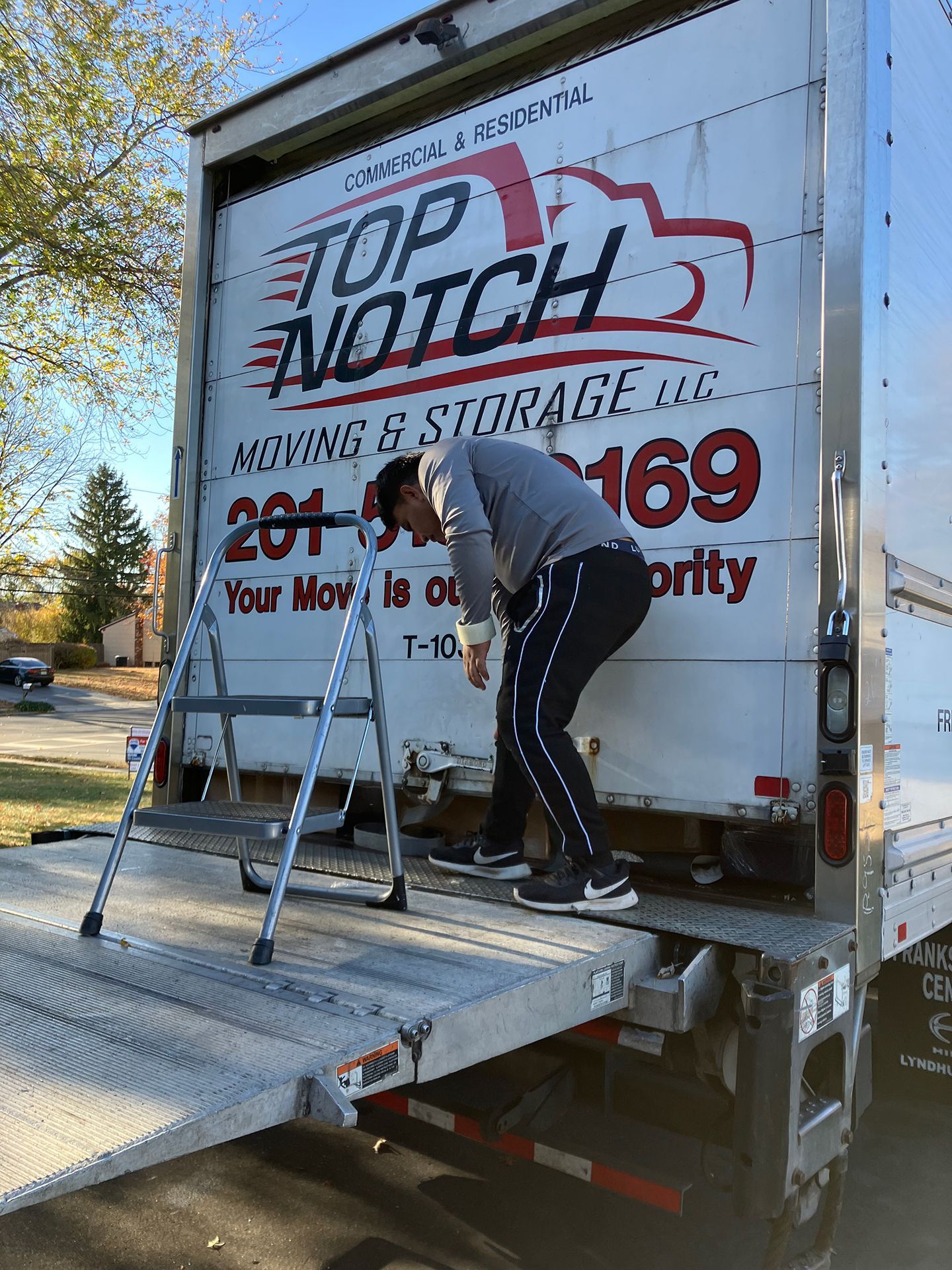 A man is standing on the back of a moving truck.
