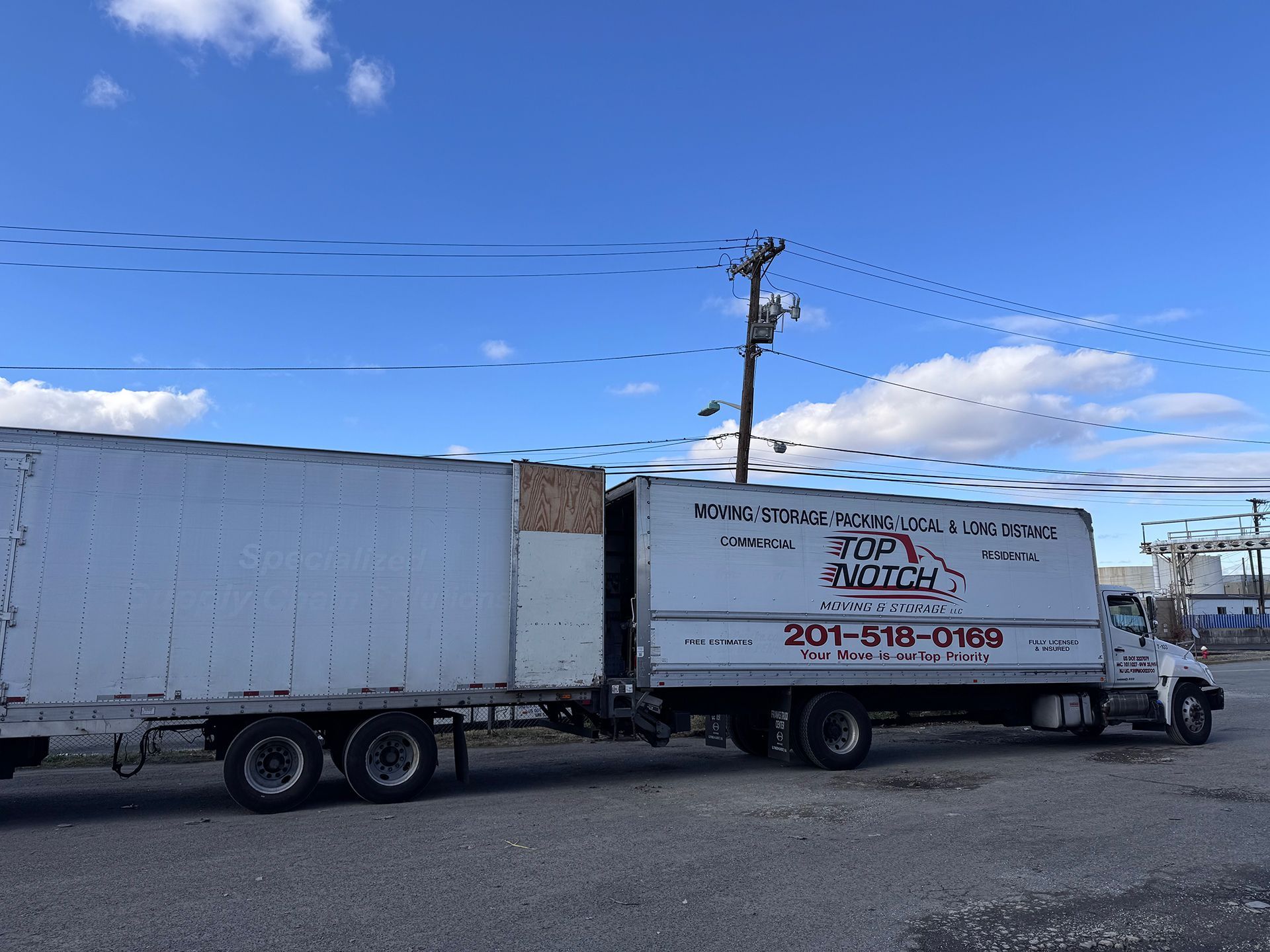 A white truck with a trailer attached to it is parked in a parking lot.