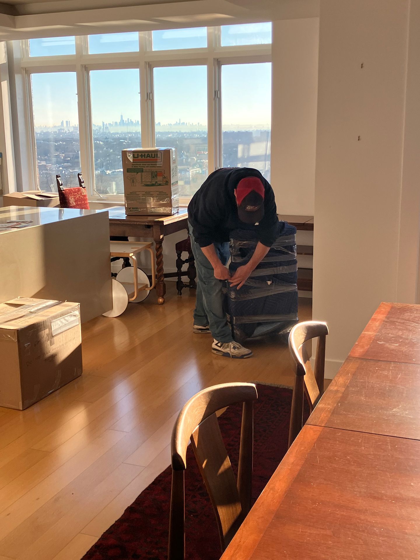 A man is kneeling down in a living room with boxes on the floor.