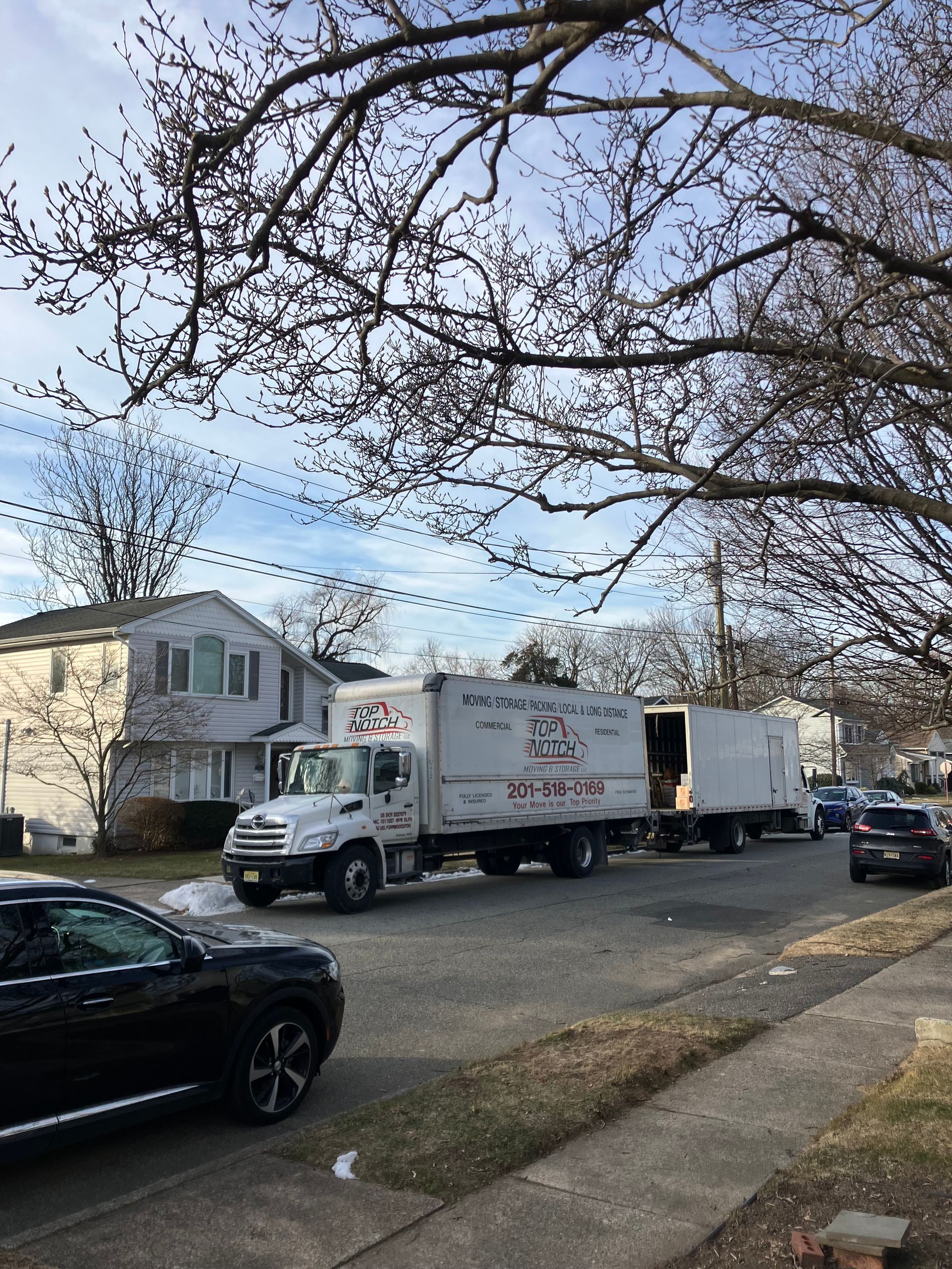 A white truck is parked on the side of the road next to a black suv.