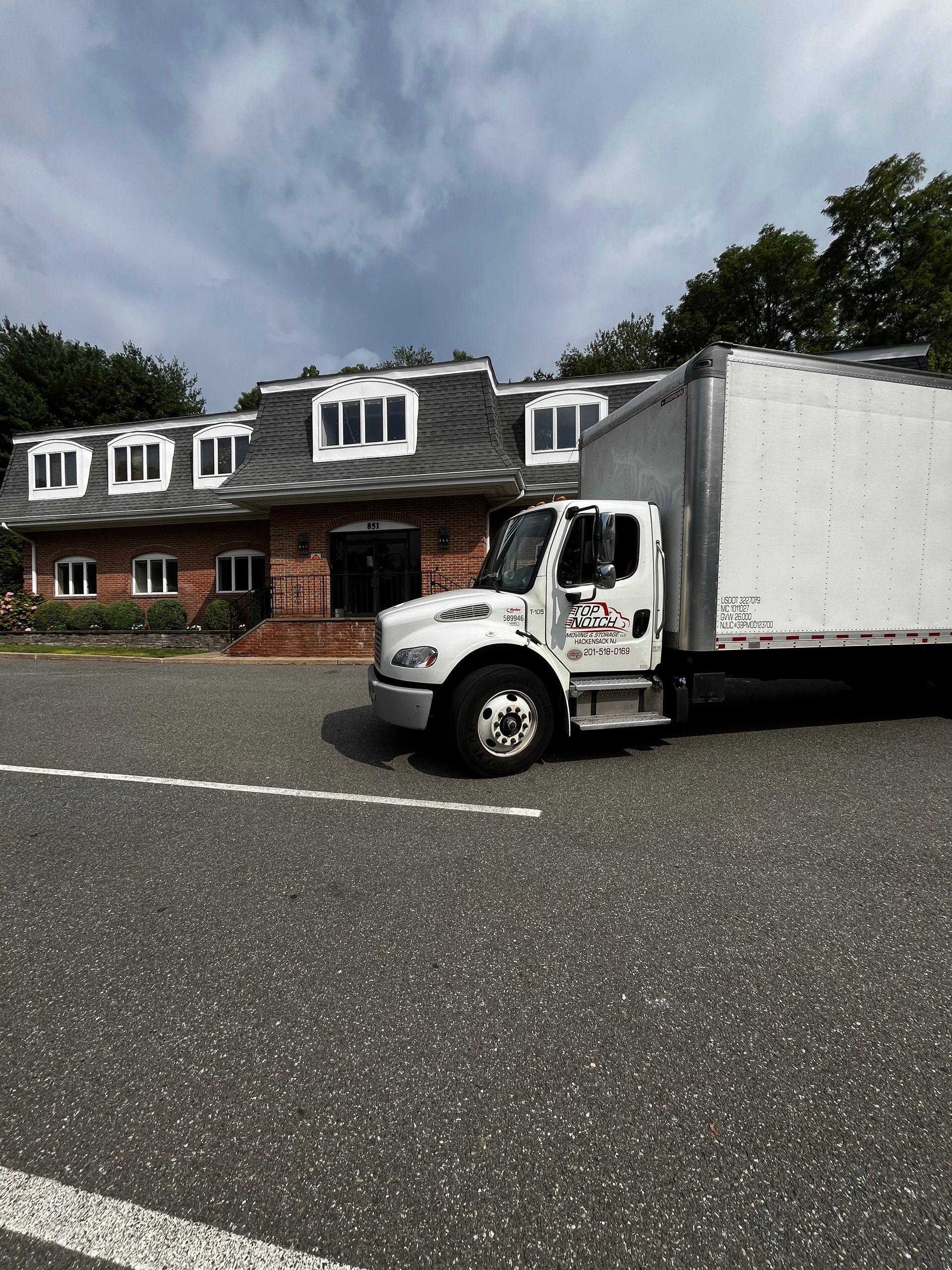 A white truck is parked in front of a large brick building.