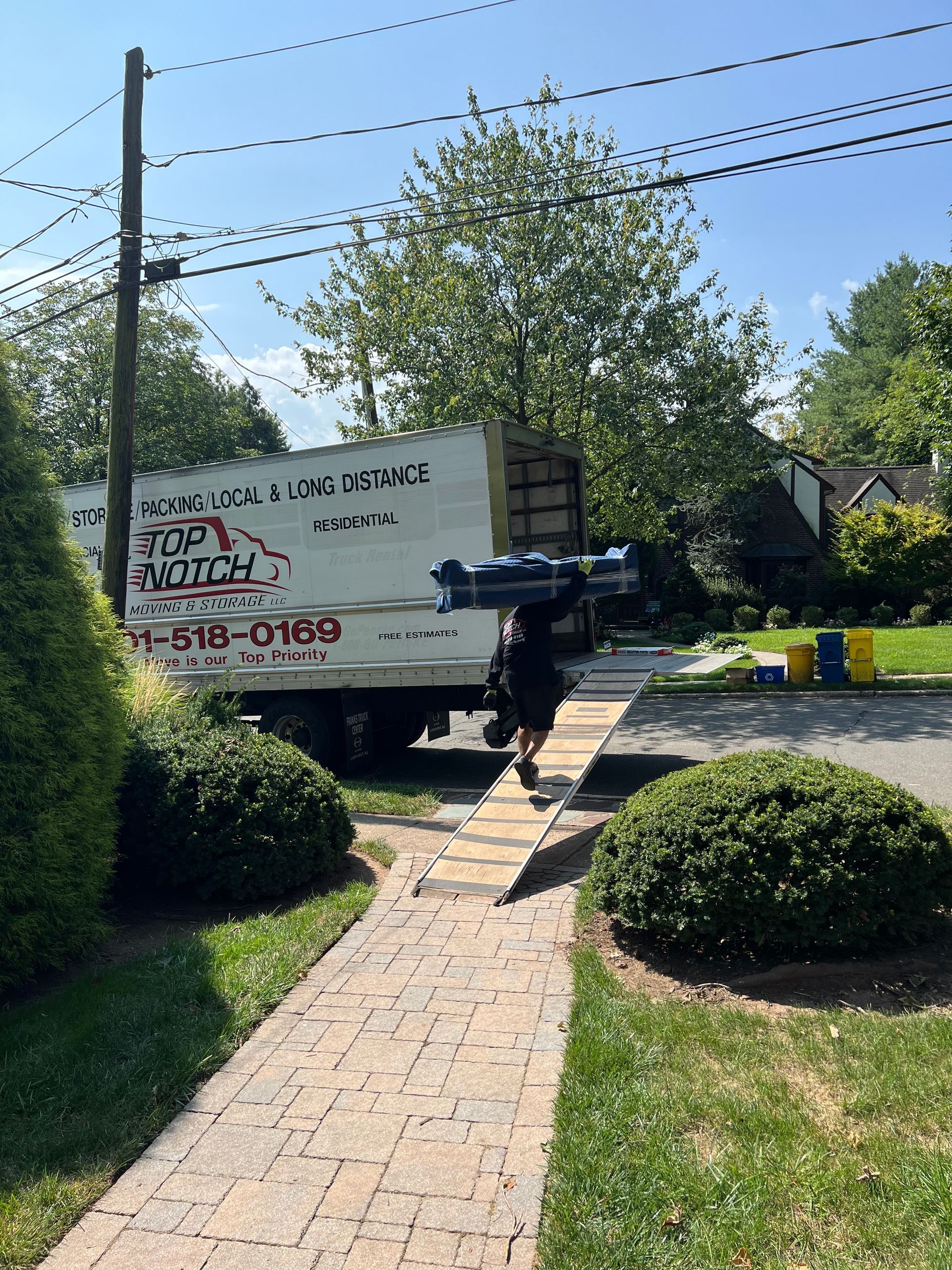 A man is walking down a sidewalk next to a moving truck.