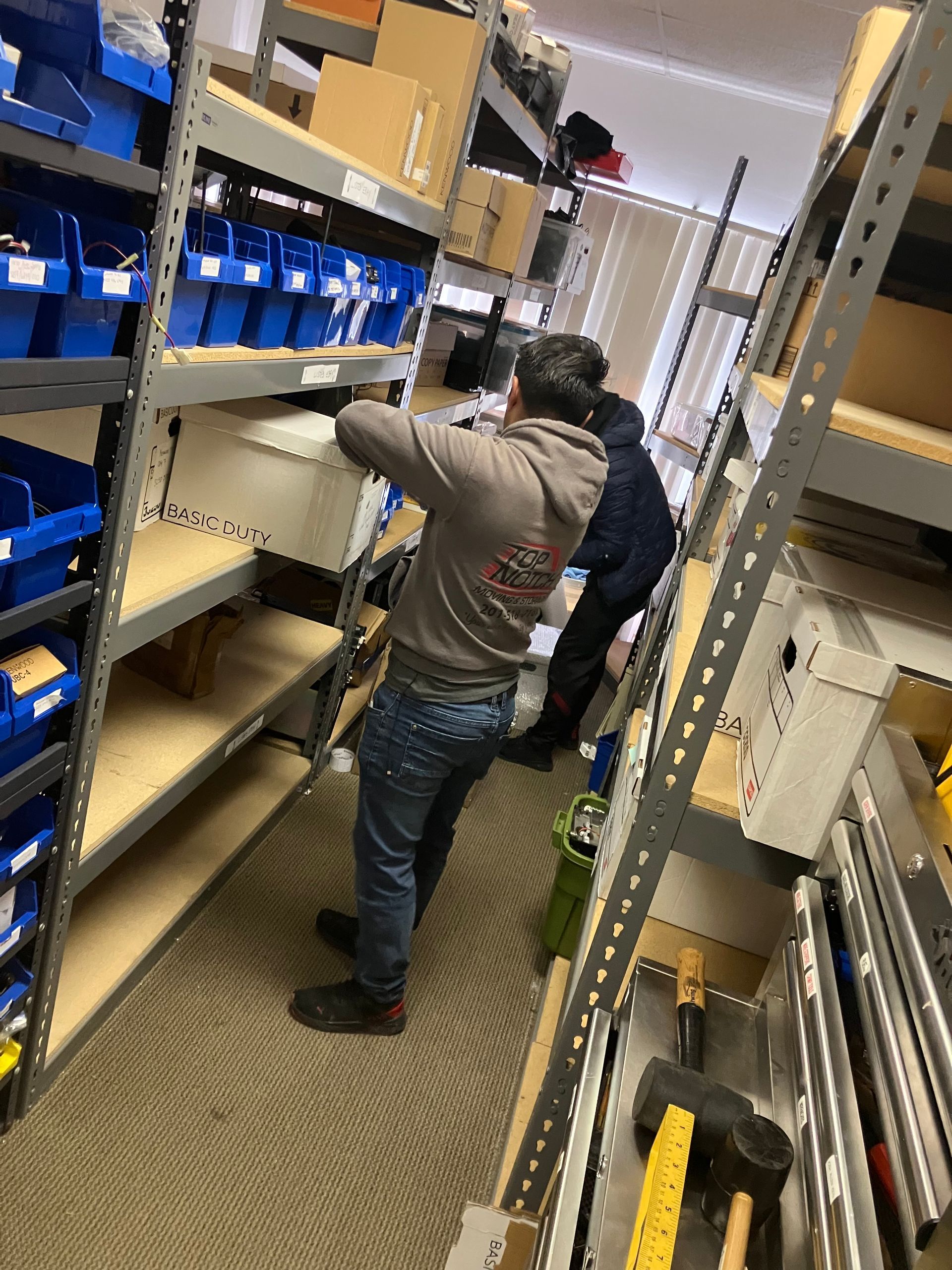 A man is standing in a warehouse looking at a box.
