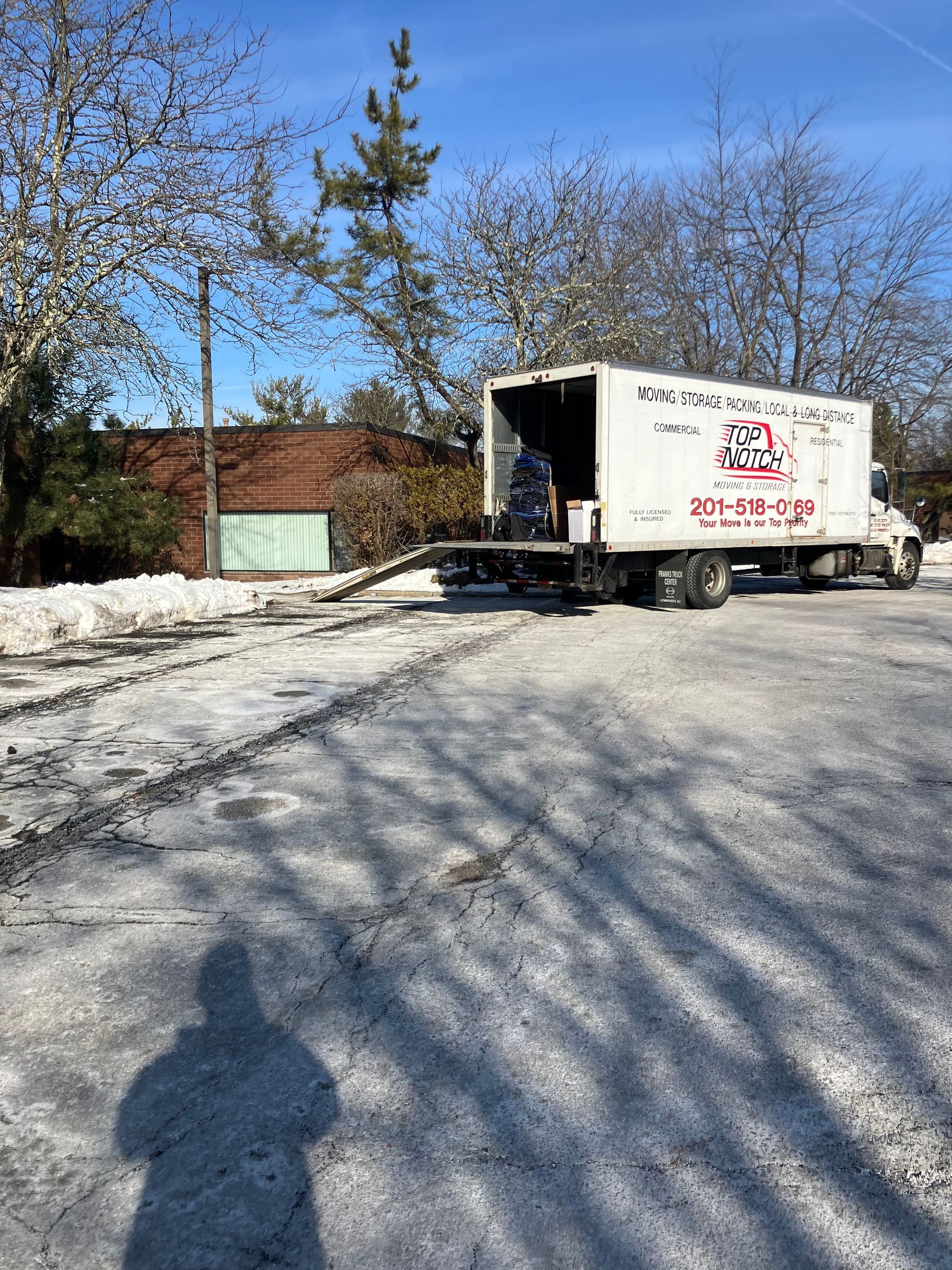 A moving truck is parked in a snowy parking lot.