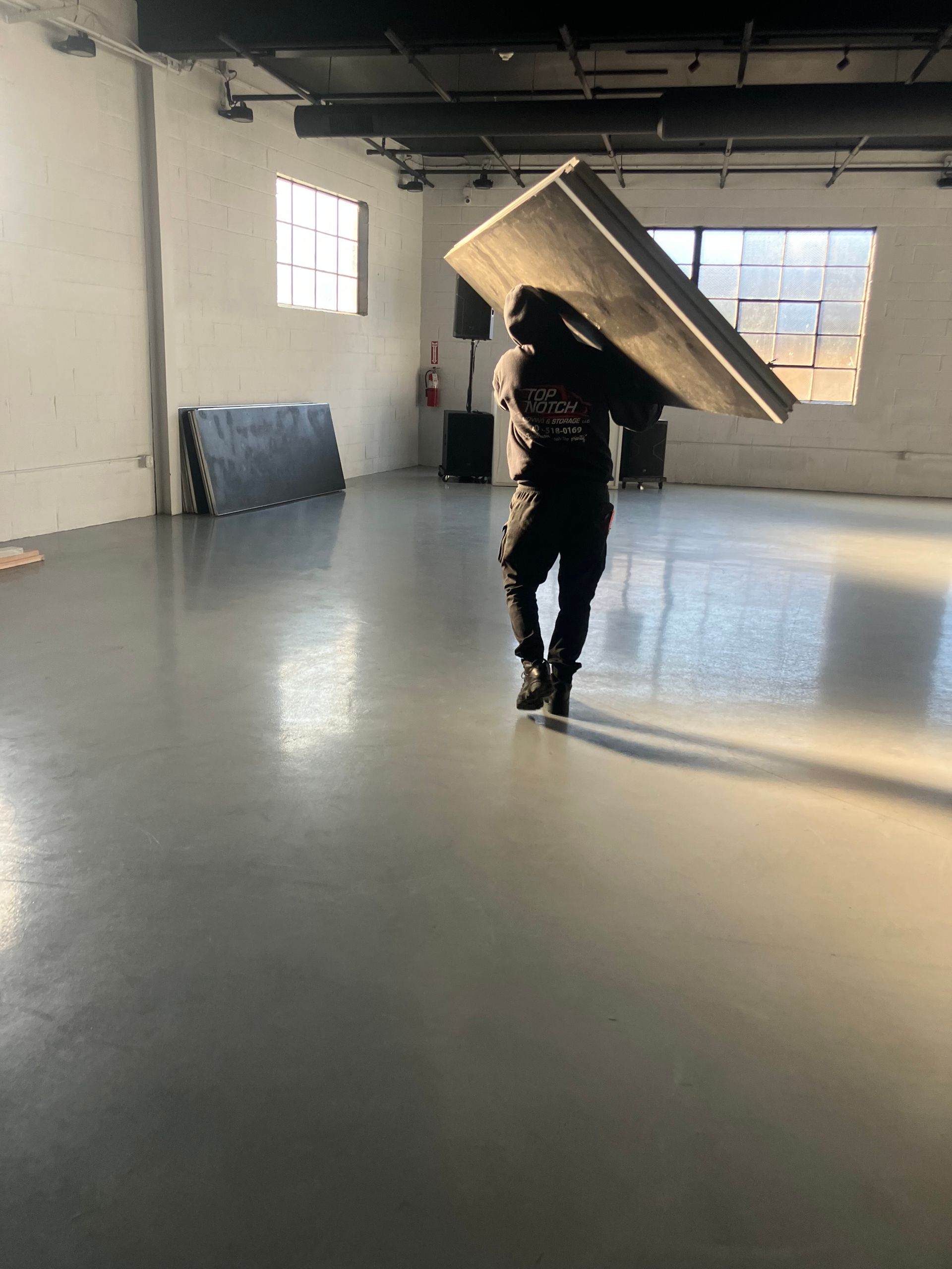 A man is carrying a large piece of wood in a room.
