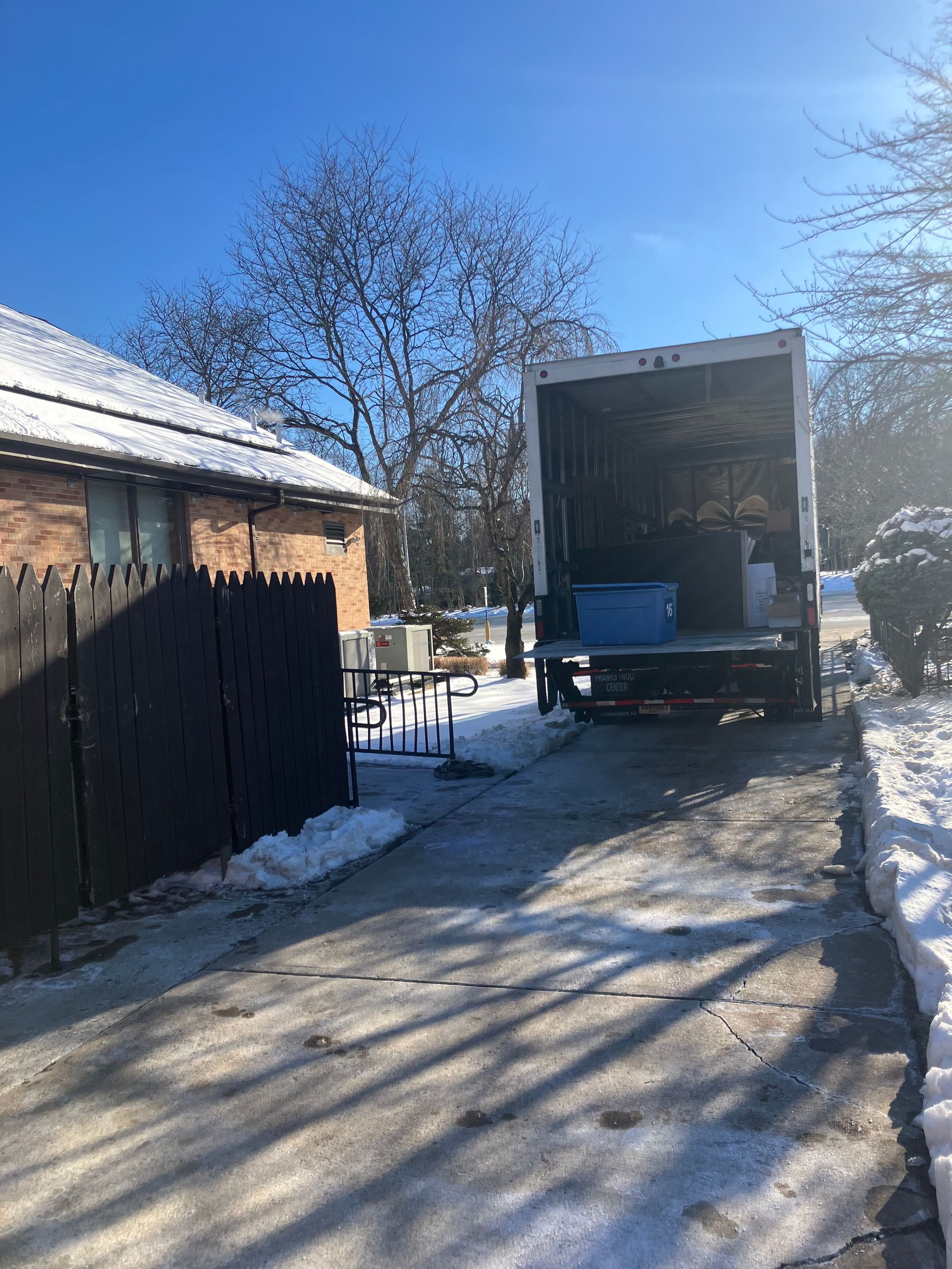 A moving truck is parked in front of a house in the snow.