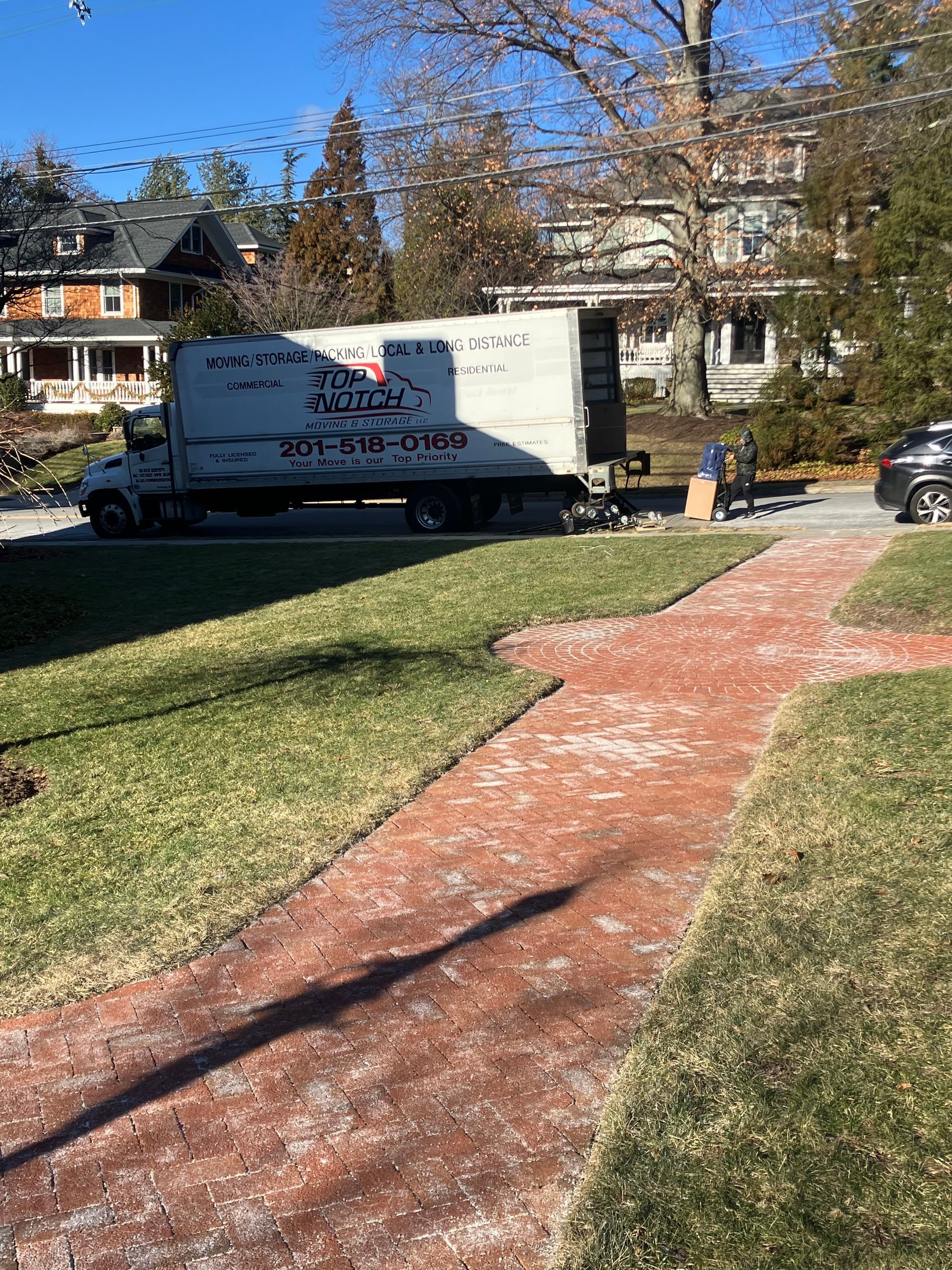 A moving truck is parked in the driveway of a house.