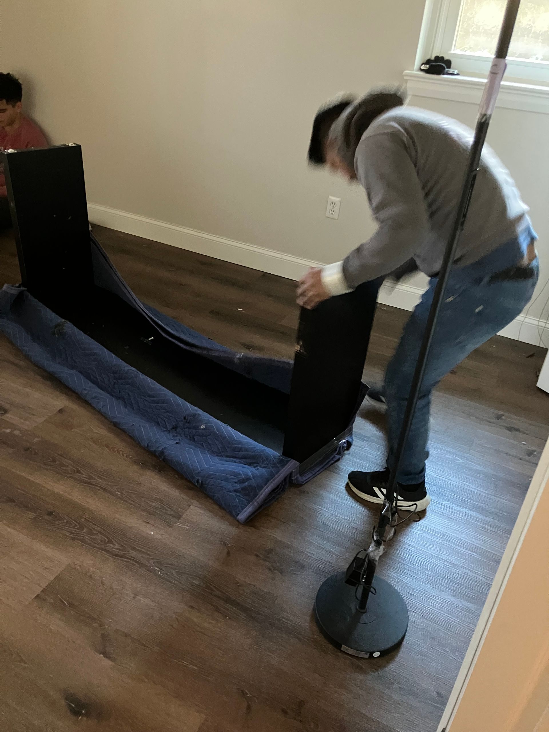 A man is moving a table in a room with a mop.