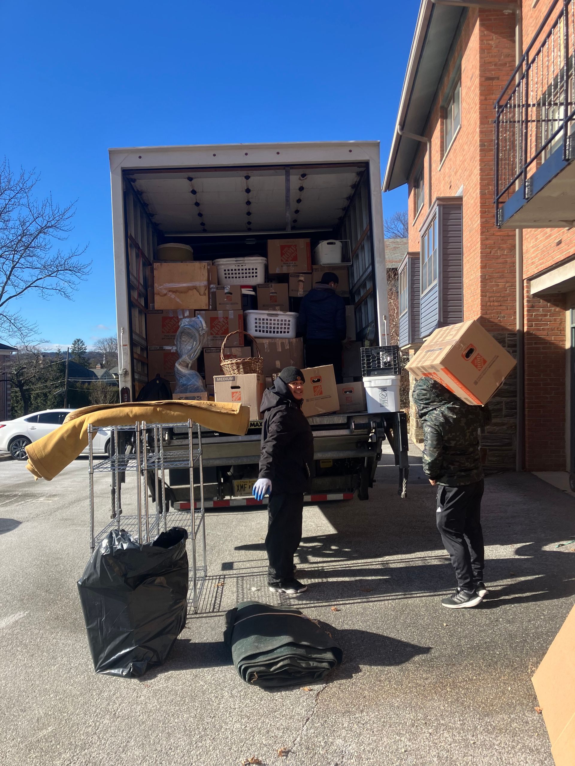 A truck is filled with boxes and people are carrying boxes on their heads.