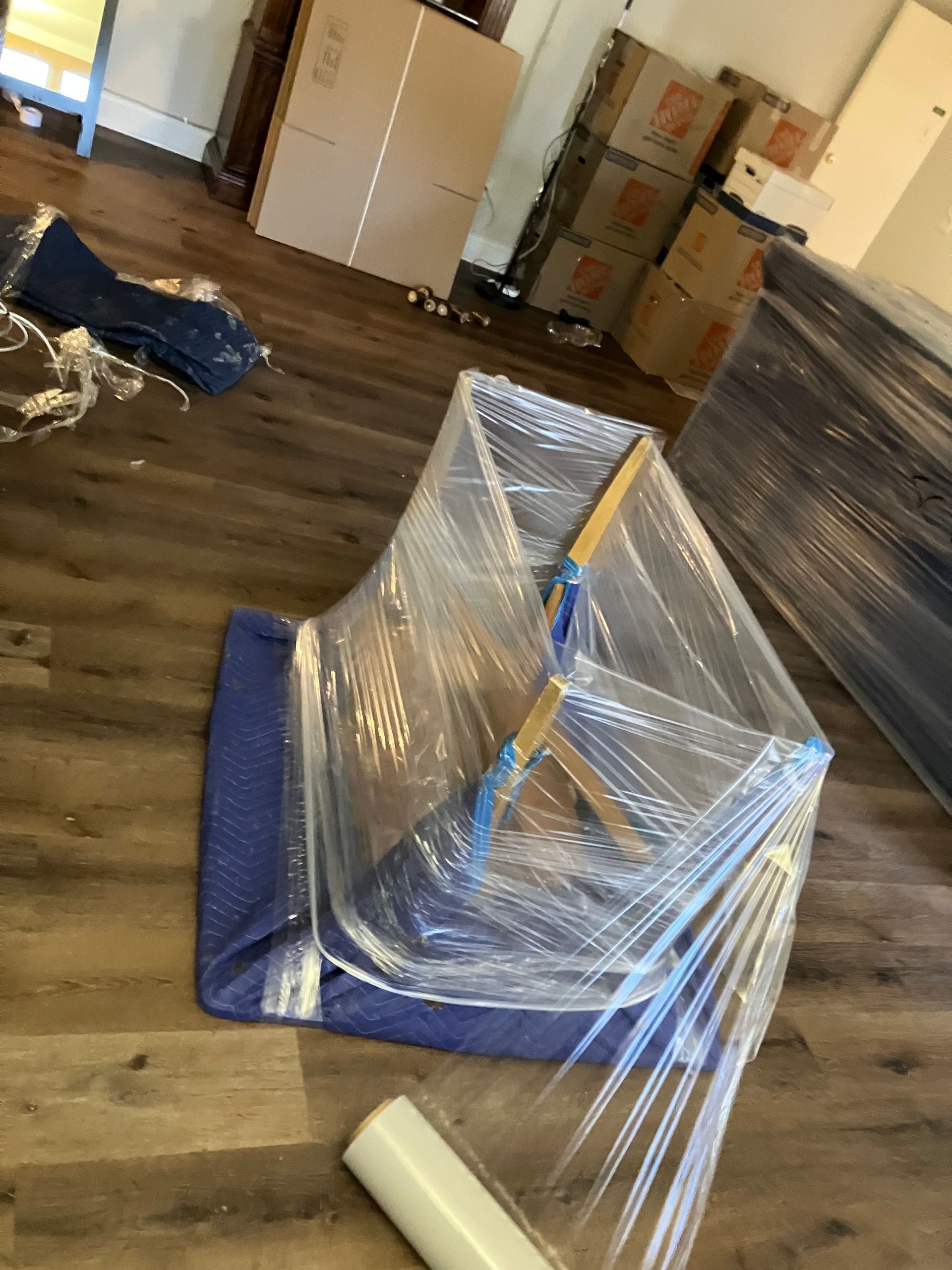 A chair is wrapped in plastic wrap in a living room.