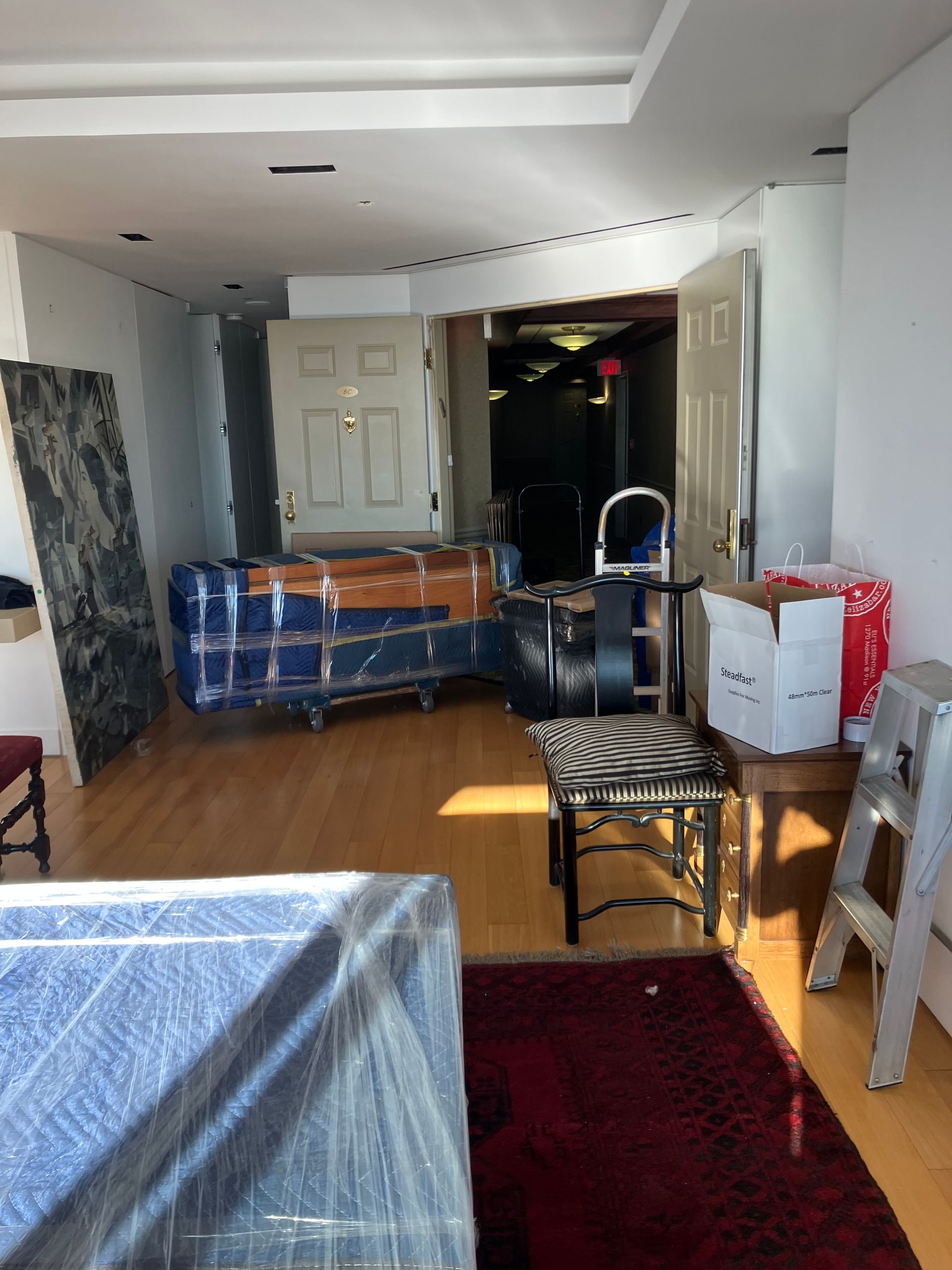 A living room filled with furniture and boxes wrapped in plastic.