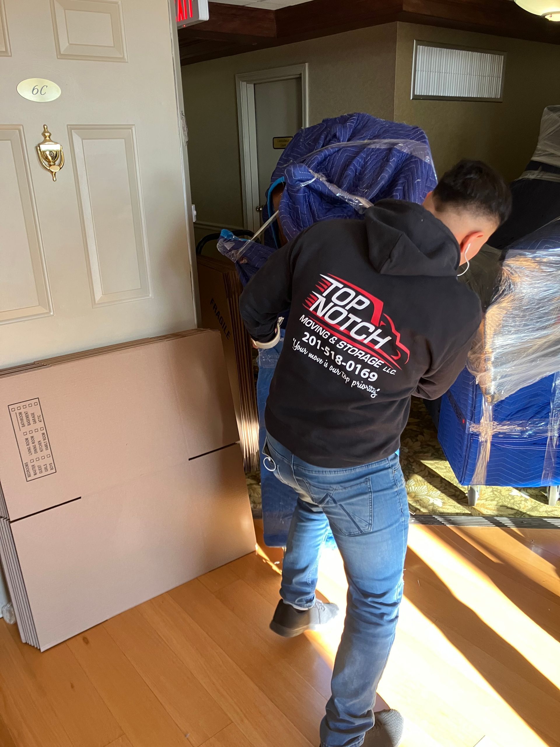 A man is carrying a large piece of furniture in a living room.