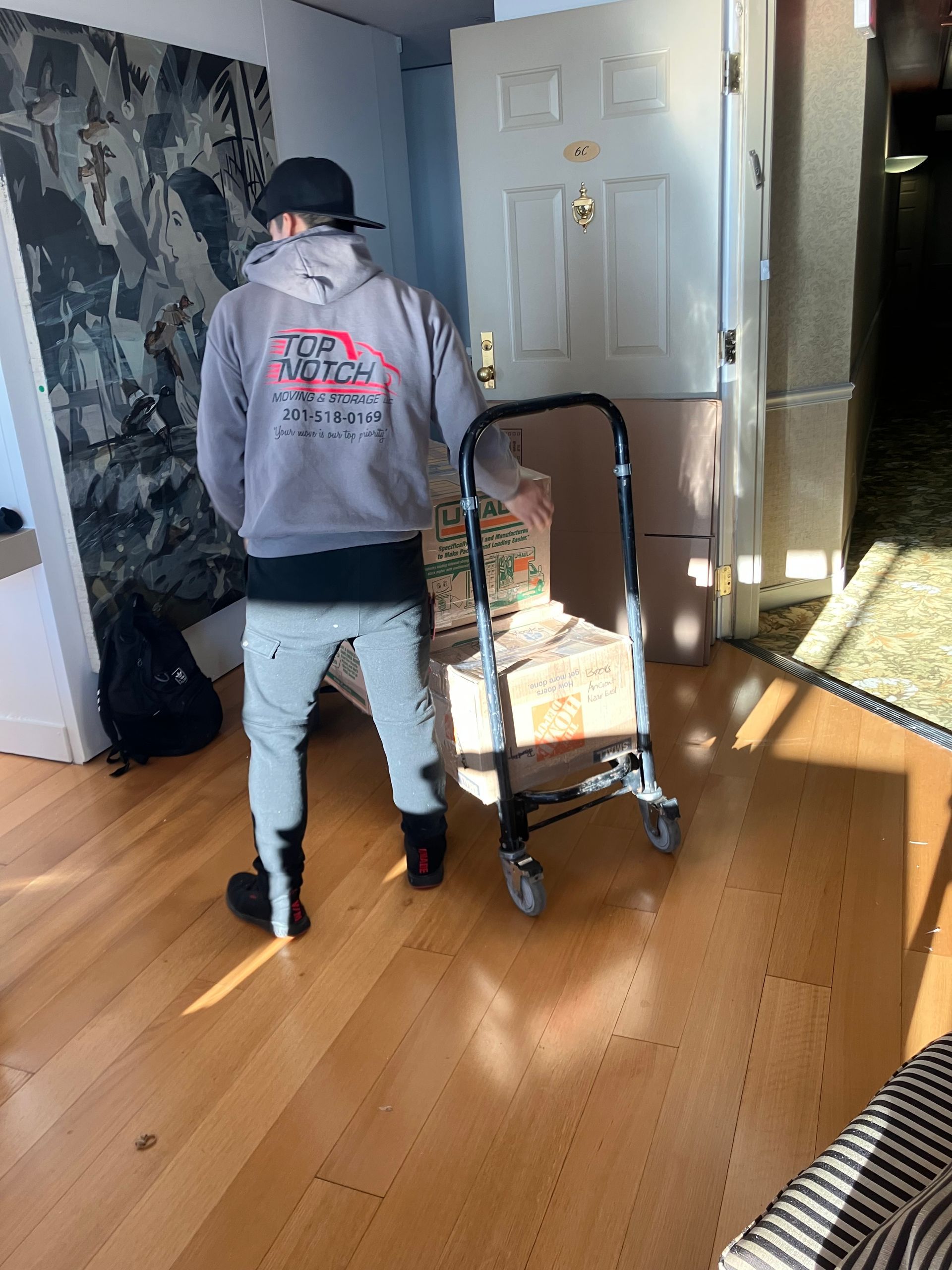 A man is pushing a cart with boxes on it in a living room.