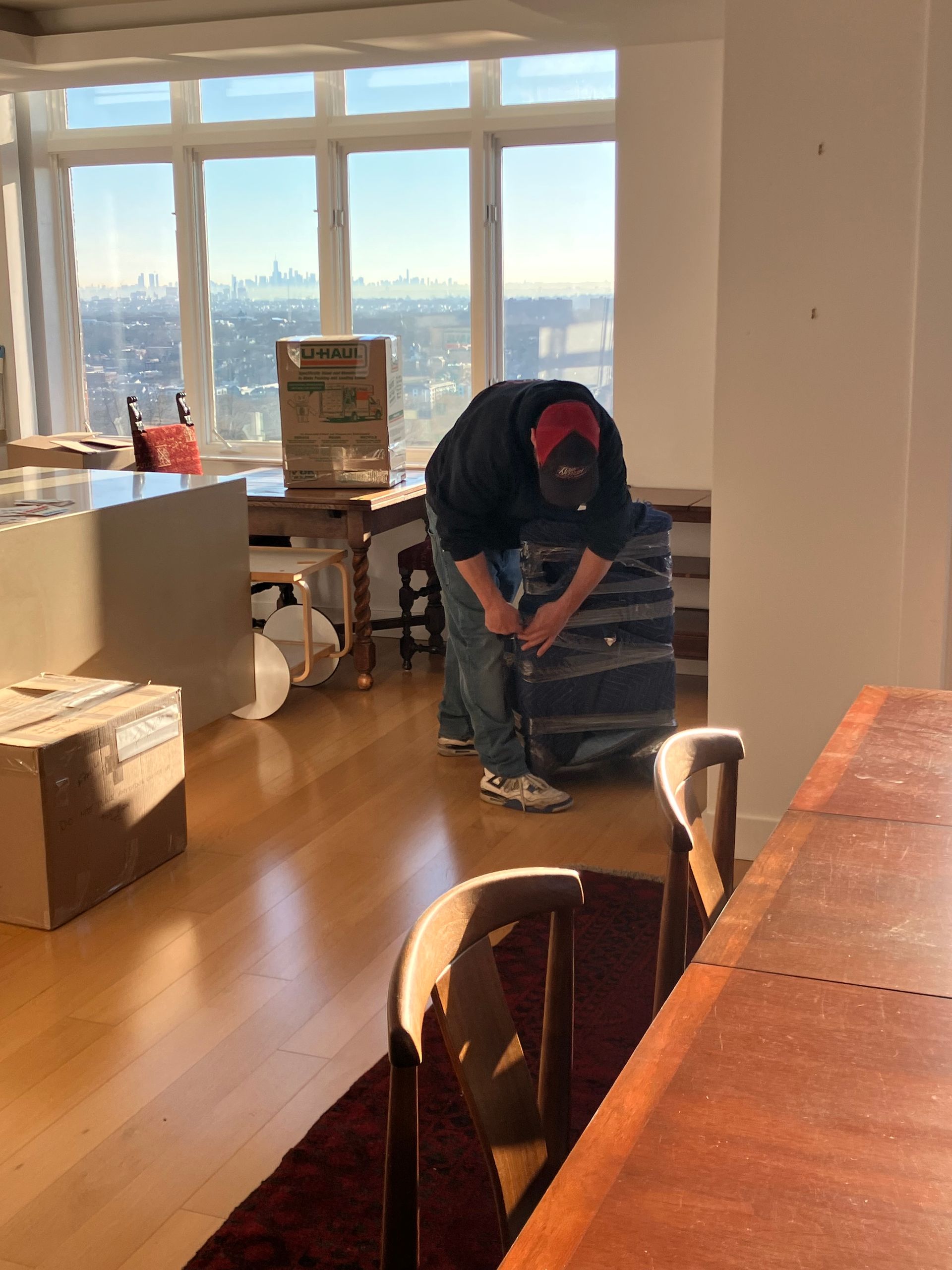 A man is kneeling down in a room with boxes on the floor