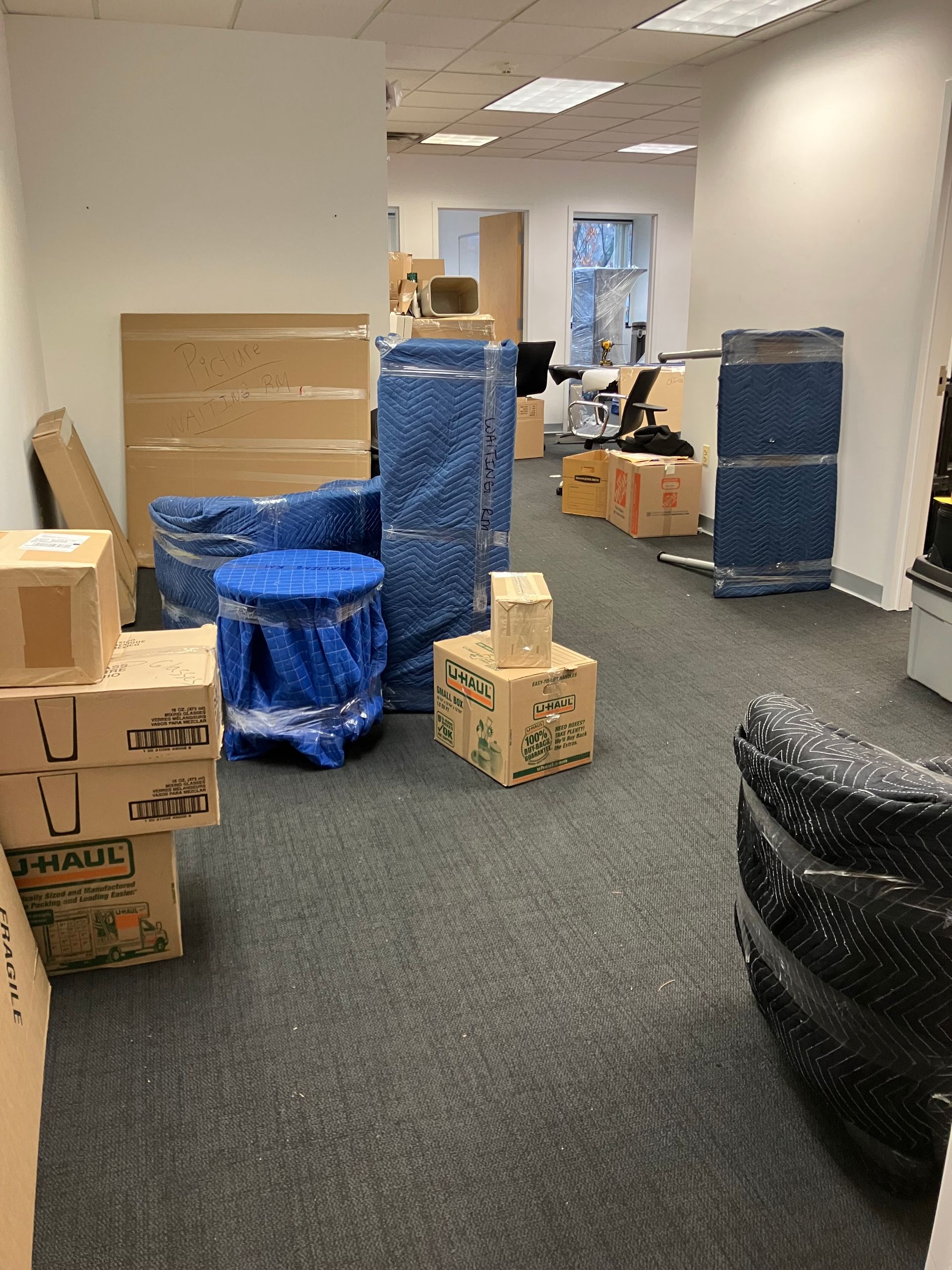 A room filled with boxes wrapped in blue plastic and stacked on top of each other.