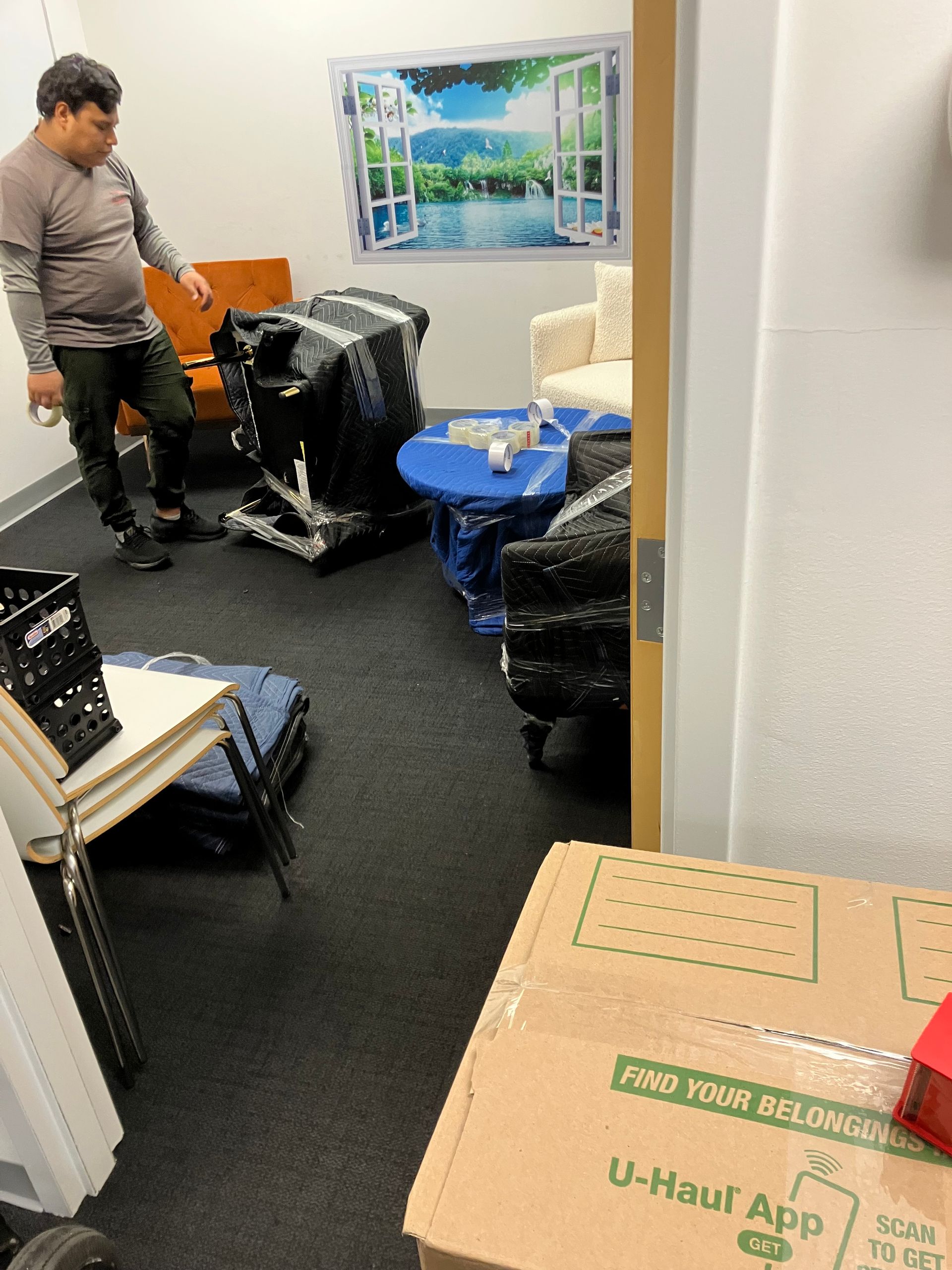 A man is standing in a room filled with boxes and chairs.