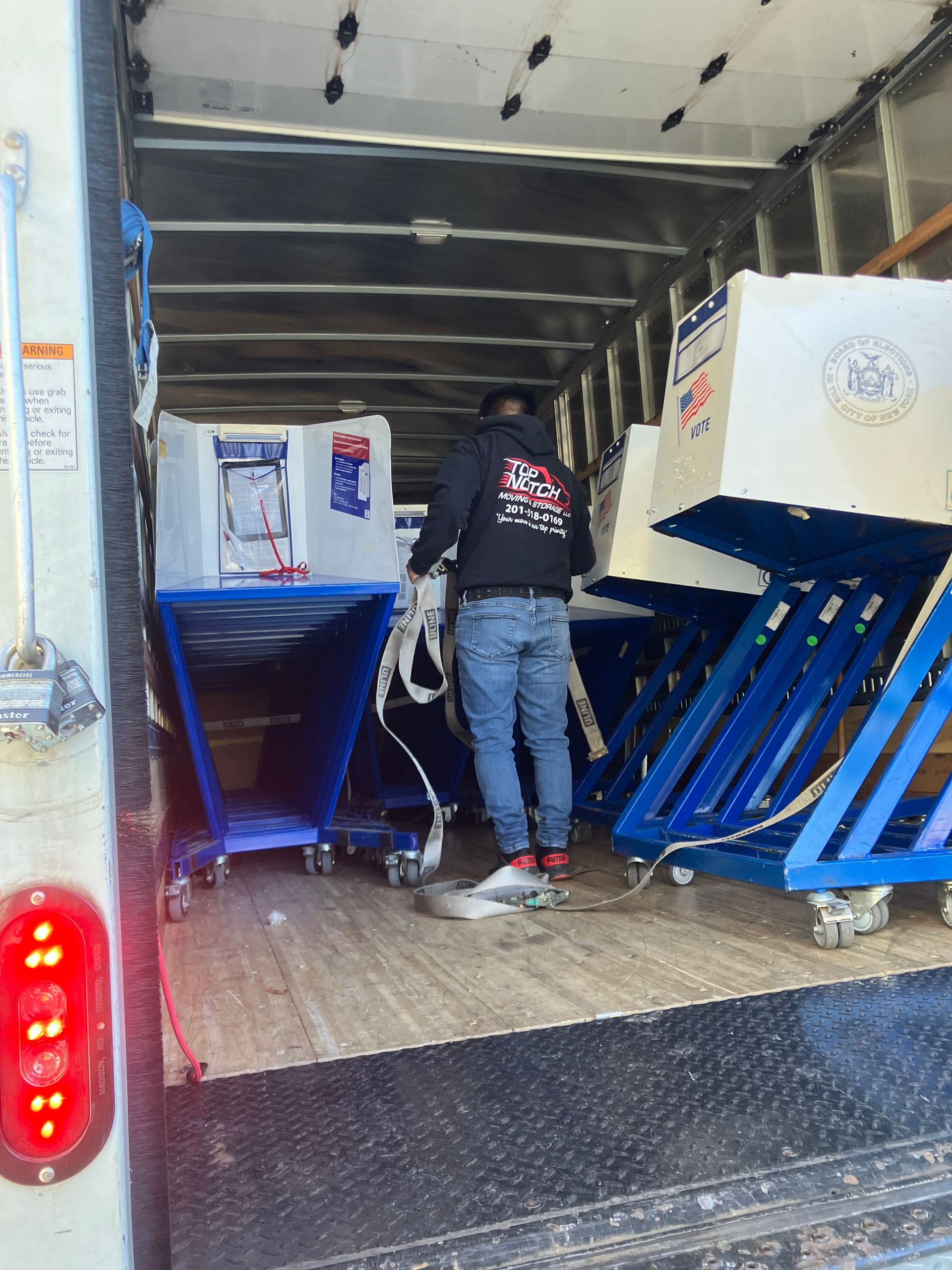 A man is loading a lift into the back of a truck.