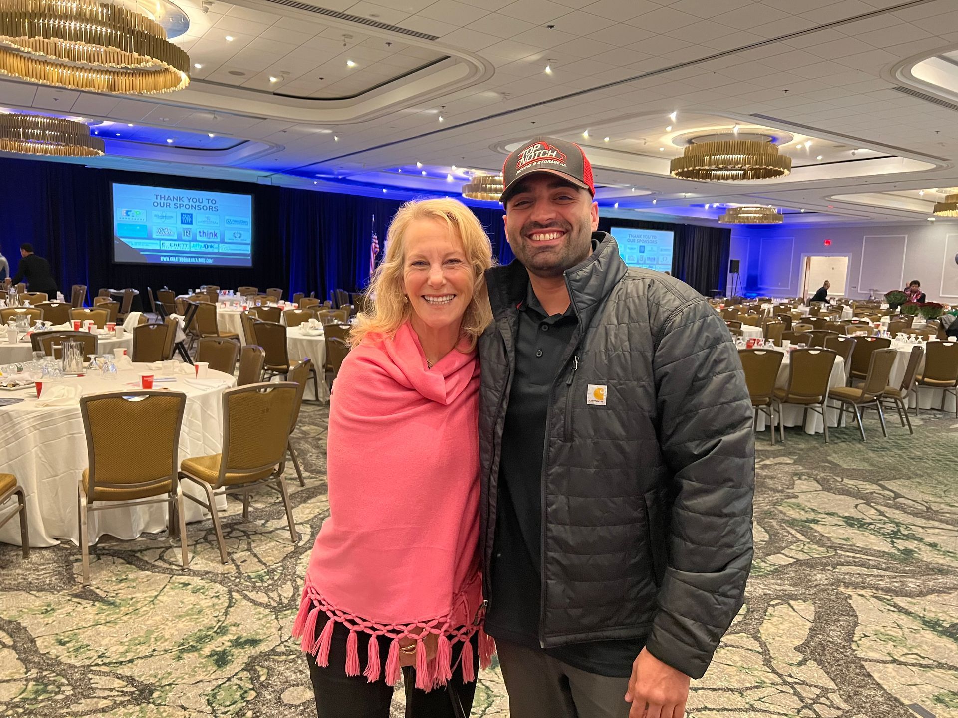 A man and a woman are posing for a picture in a large room.