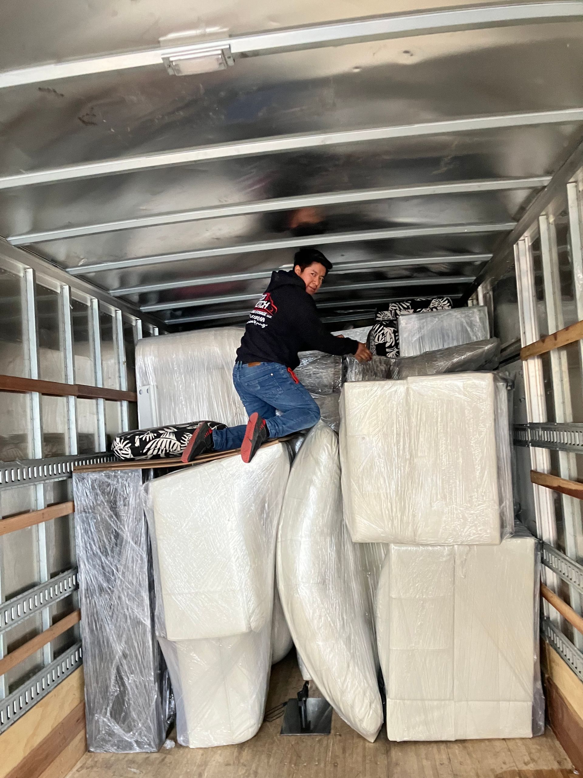 A man is standing in the back of a moving truck.
