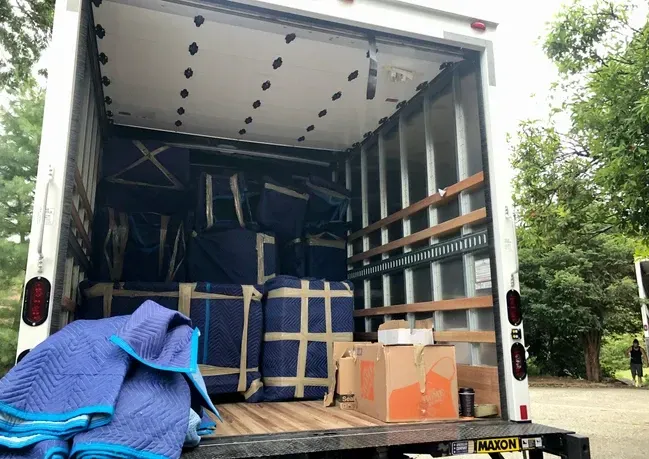 The back of a moving truck filled with boxes and blankets