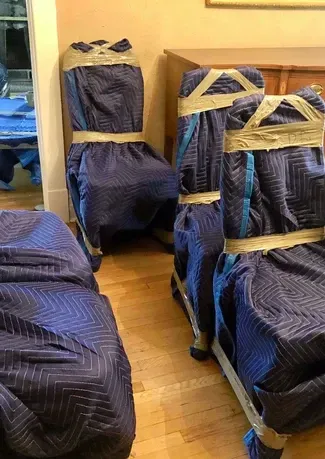A room filled with chairs wrapped in blue blankets and tape