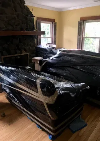 A living room with a couch wrapped in plastic and a fireplace