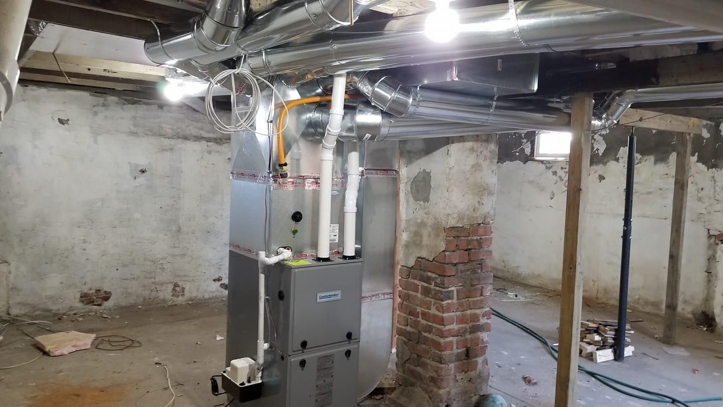 Furnace installation in a basement with exposed brick and ductwork.