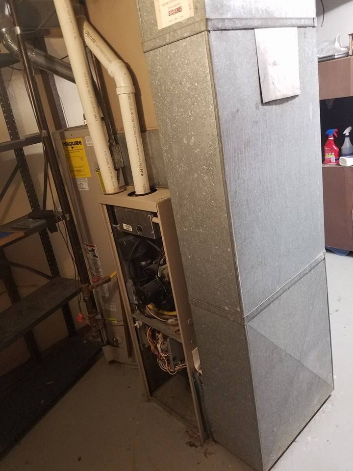 Furnace in a utility room with metal ductwork, stairs and a shelf.