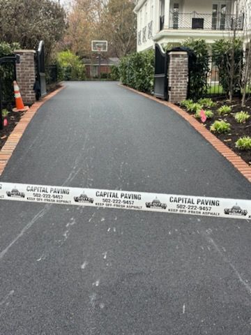 A freshly paved driveway with brick edging, blocked by a 