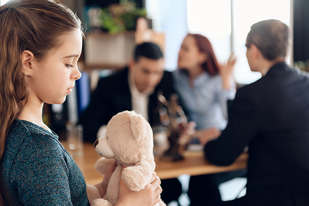 Girl holding a teddy bear in a blurred office meeting scene