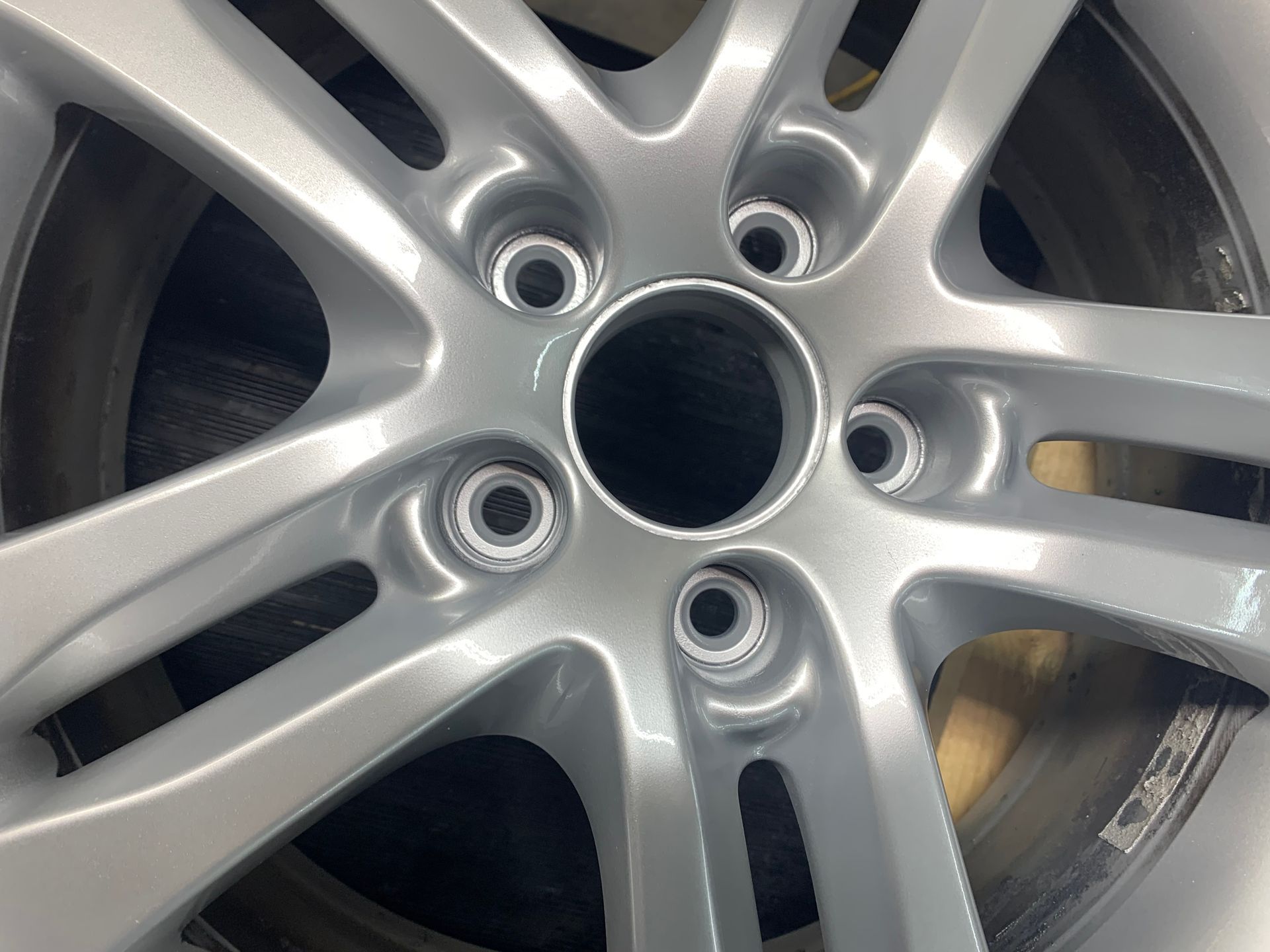 Close-up of a silver car wheel rim with five lug holes and a visible tire edge