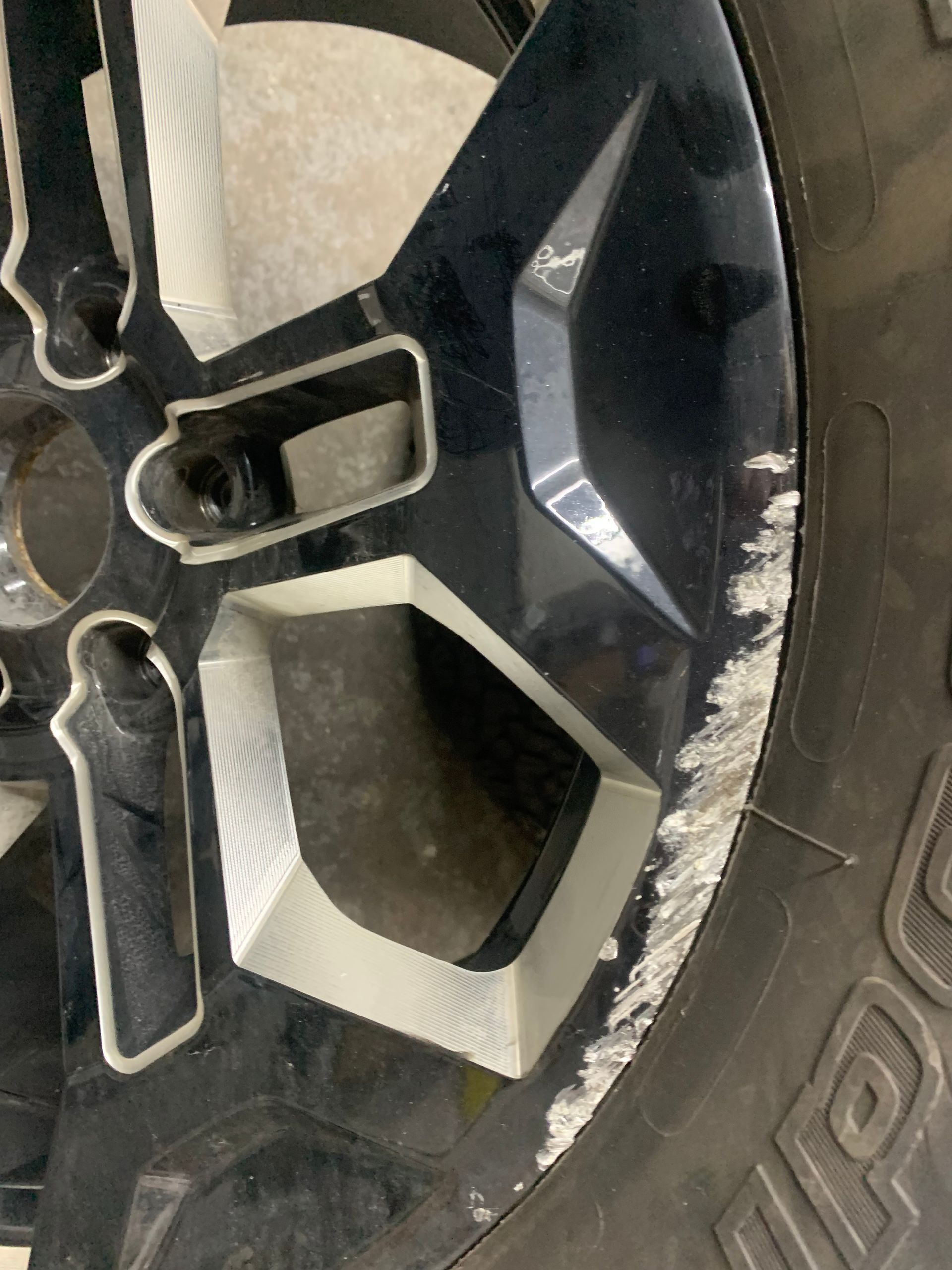 Close-up of a black car wheel with silver rim and white scuff marks on the tire edge