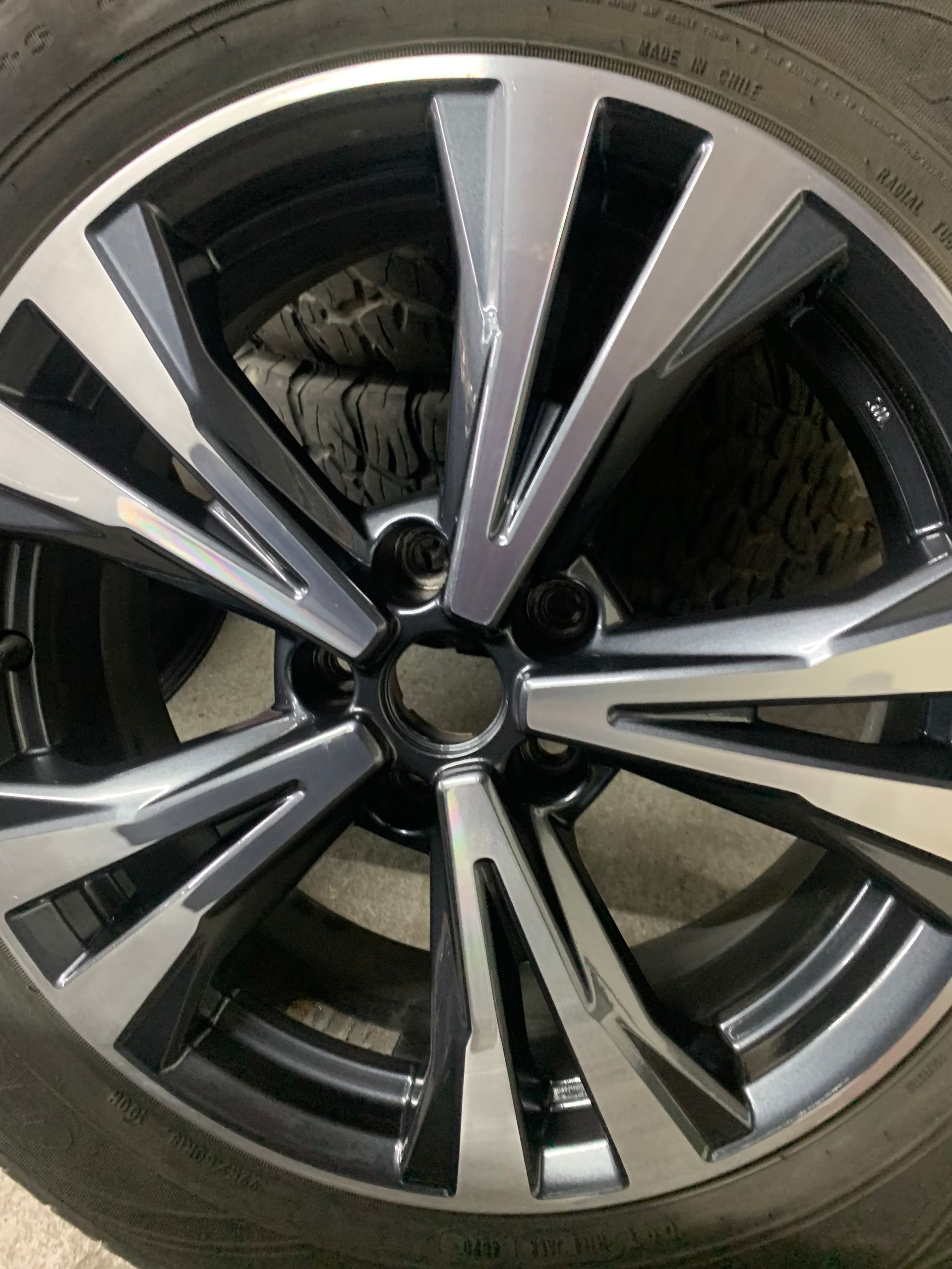 Close-up of a silver and black car alloy wheel with a tire and visible brake components