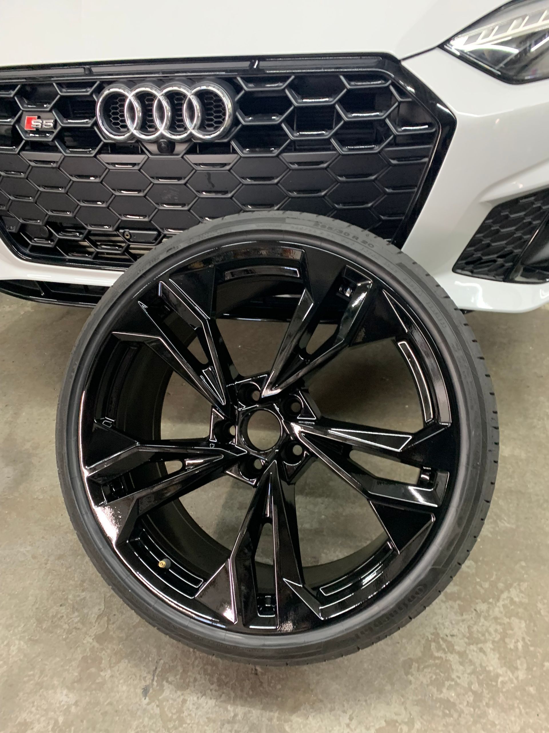 Black Audi-style alloy wheel in front of a silver Audi grille