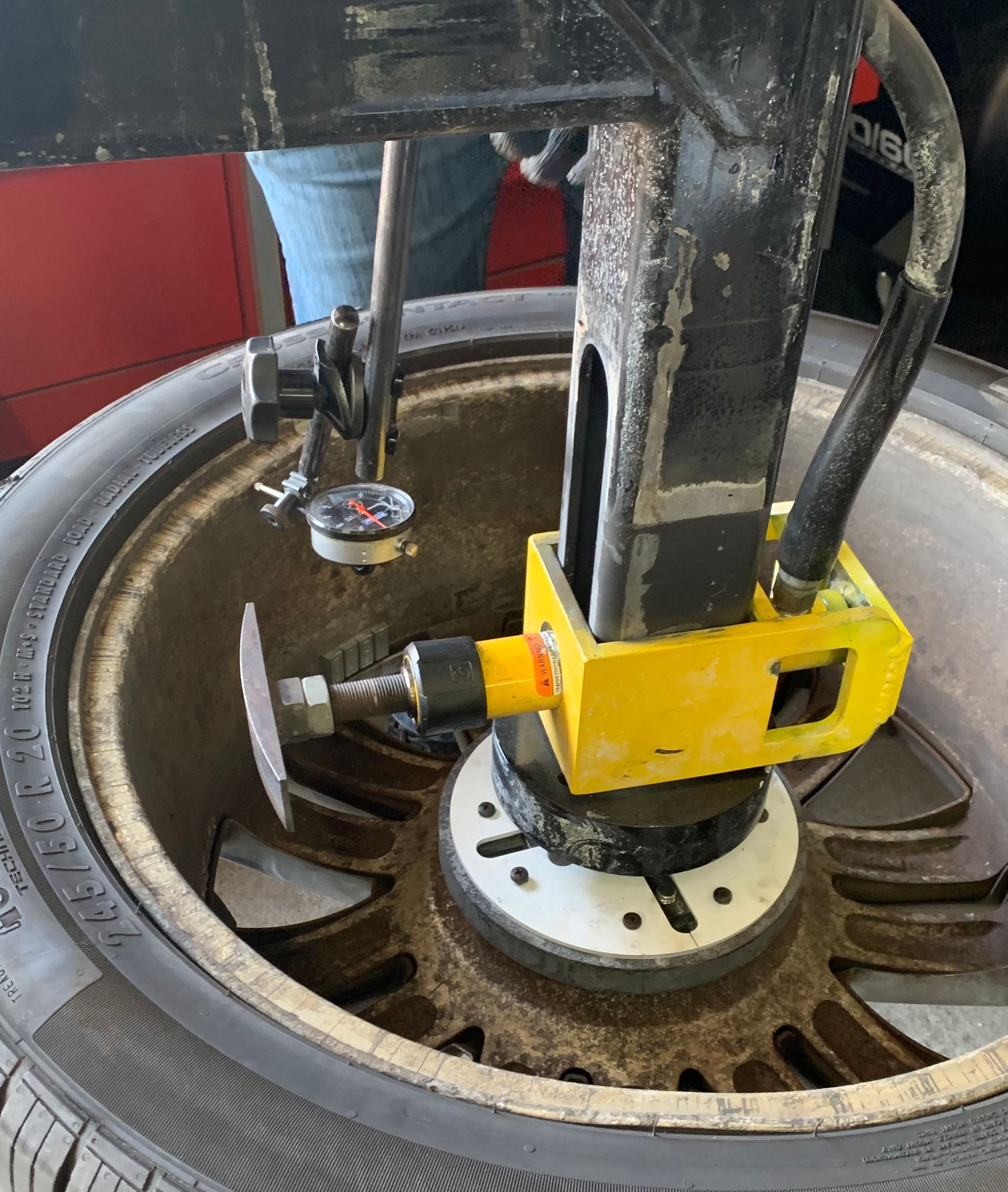 Yellow wheel alignment machine clamped to a car tire in a workshop