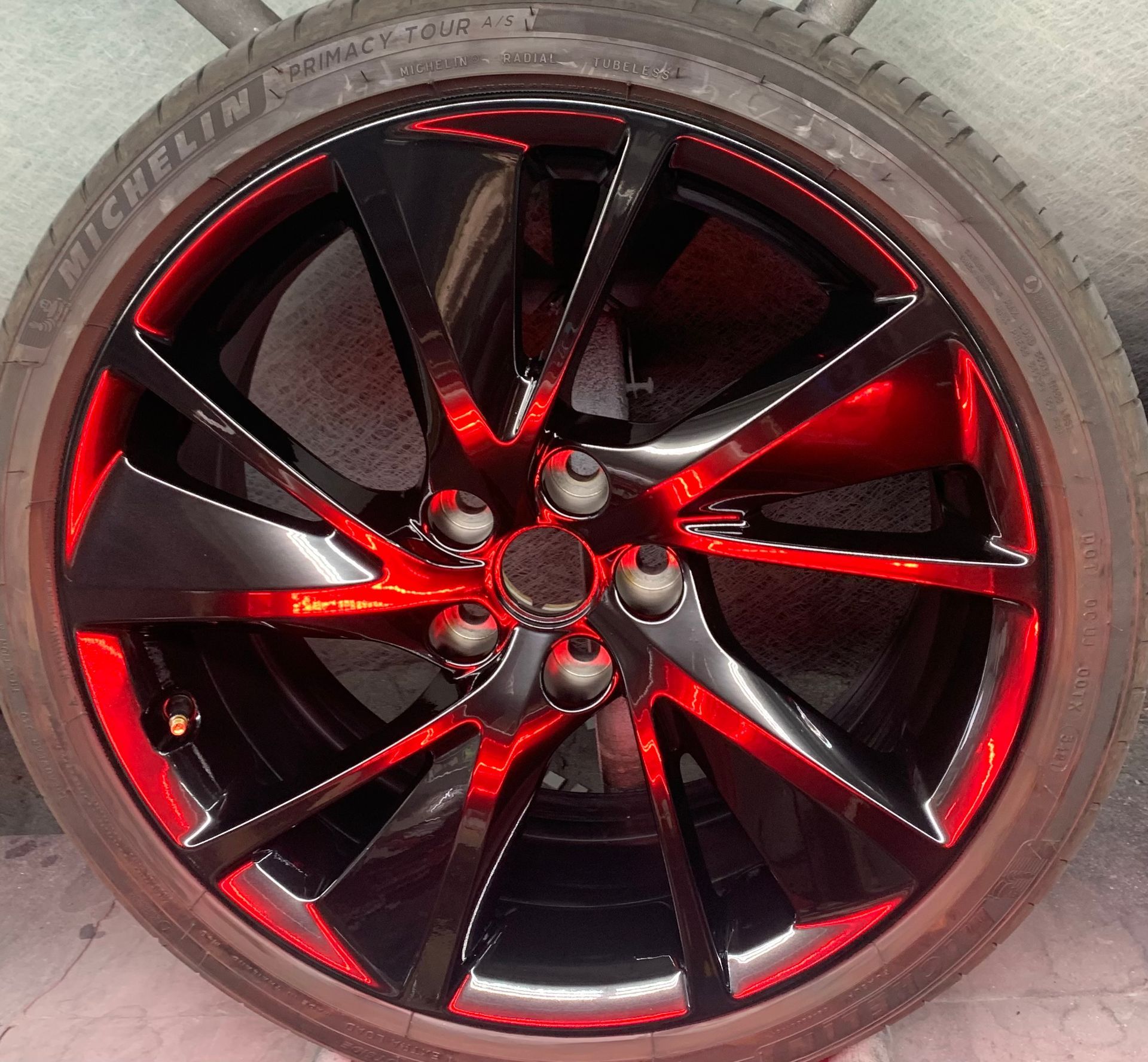 Close-up of a red-and-black alloy car wheel rim with tire, viewed front-on.