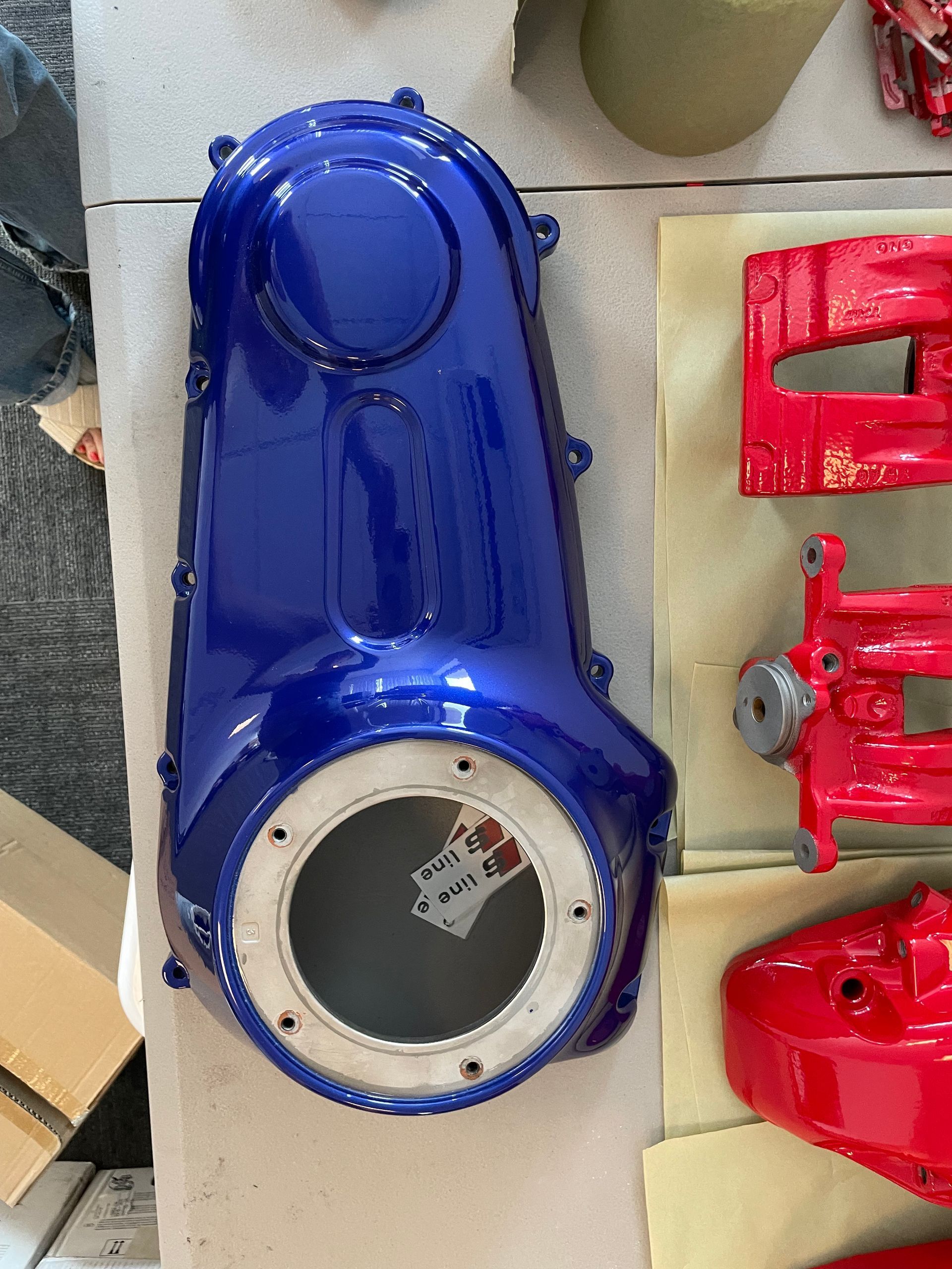 Blue industrial machine housing beside red mechanical parts on a workshop floor