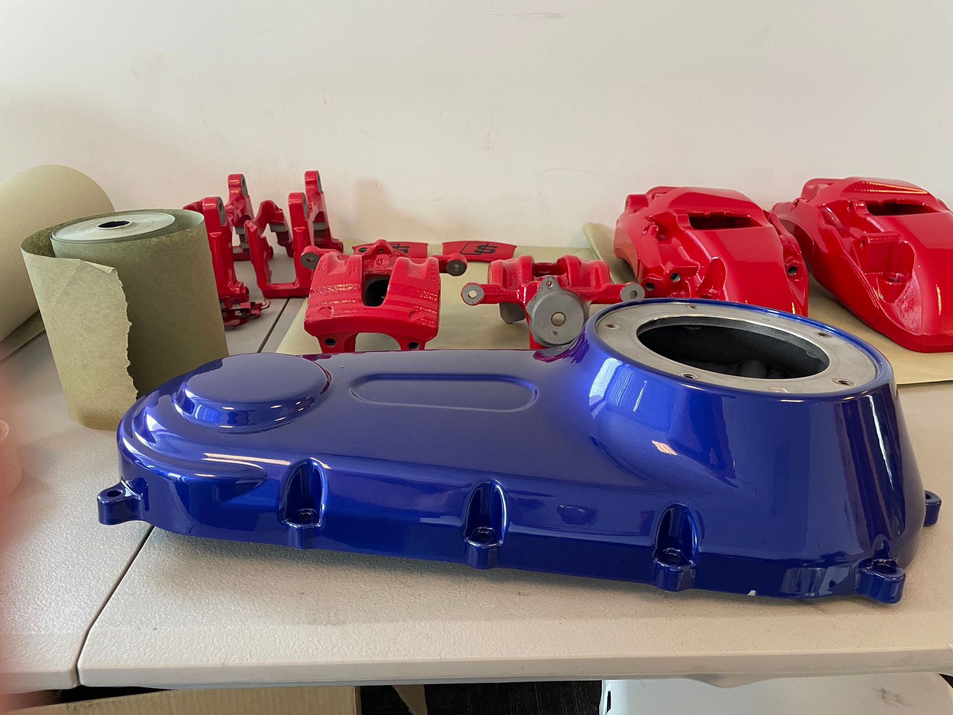 Assorted 3D-printed parts in red and blue on a tabletop, including a large blue casing in front