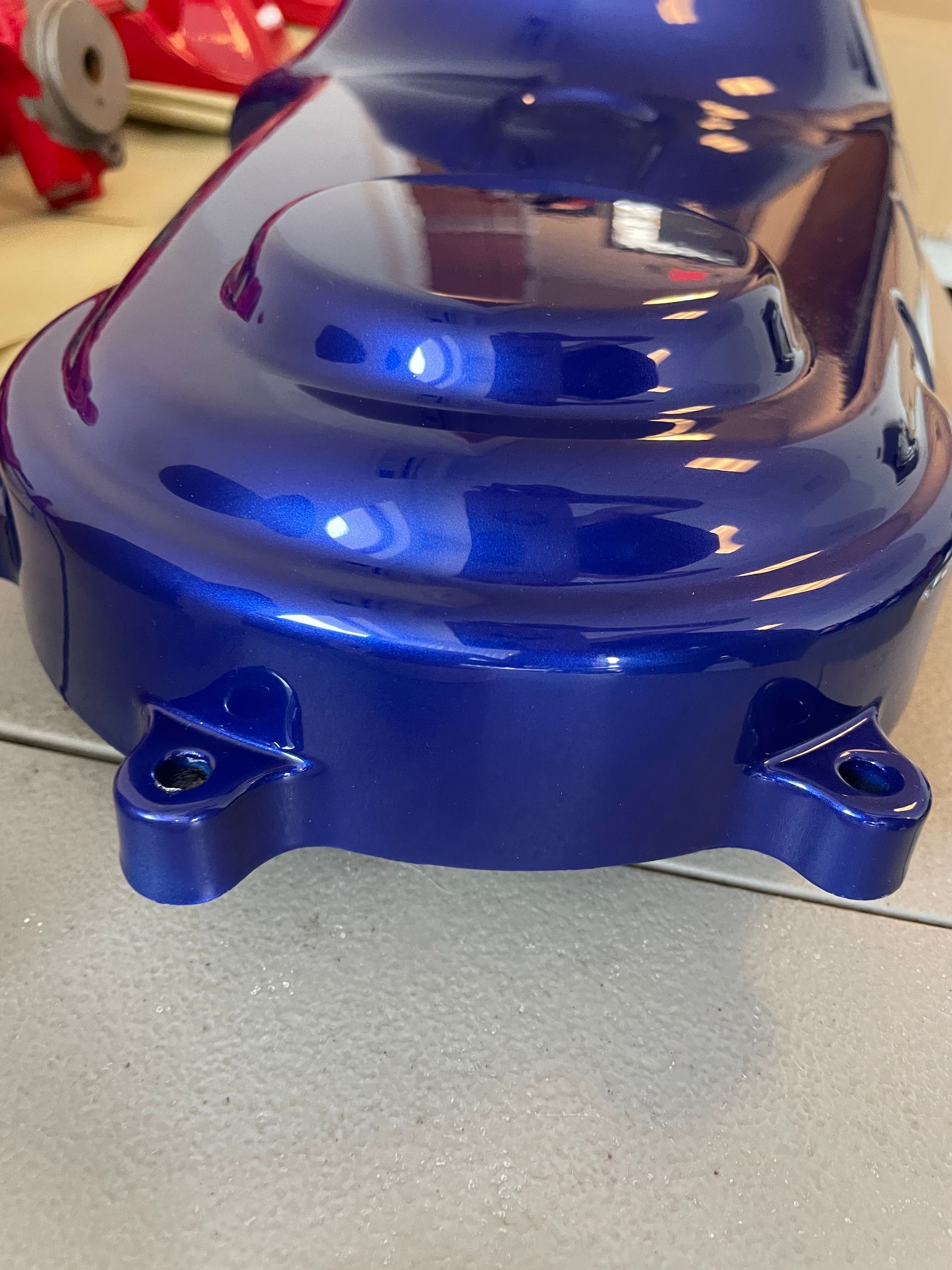 Glossy blue plastic mechanical housing with rounded top and mounting tabs on a tabletop
