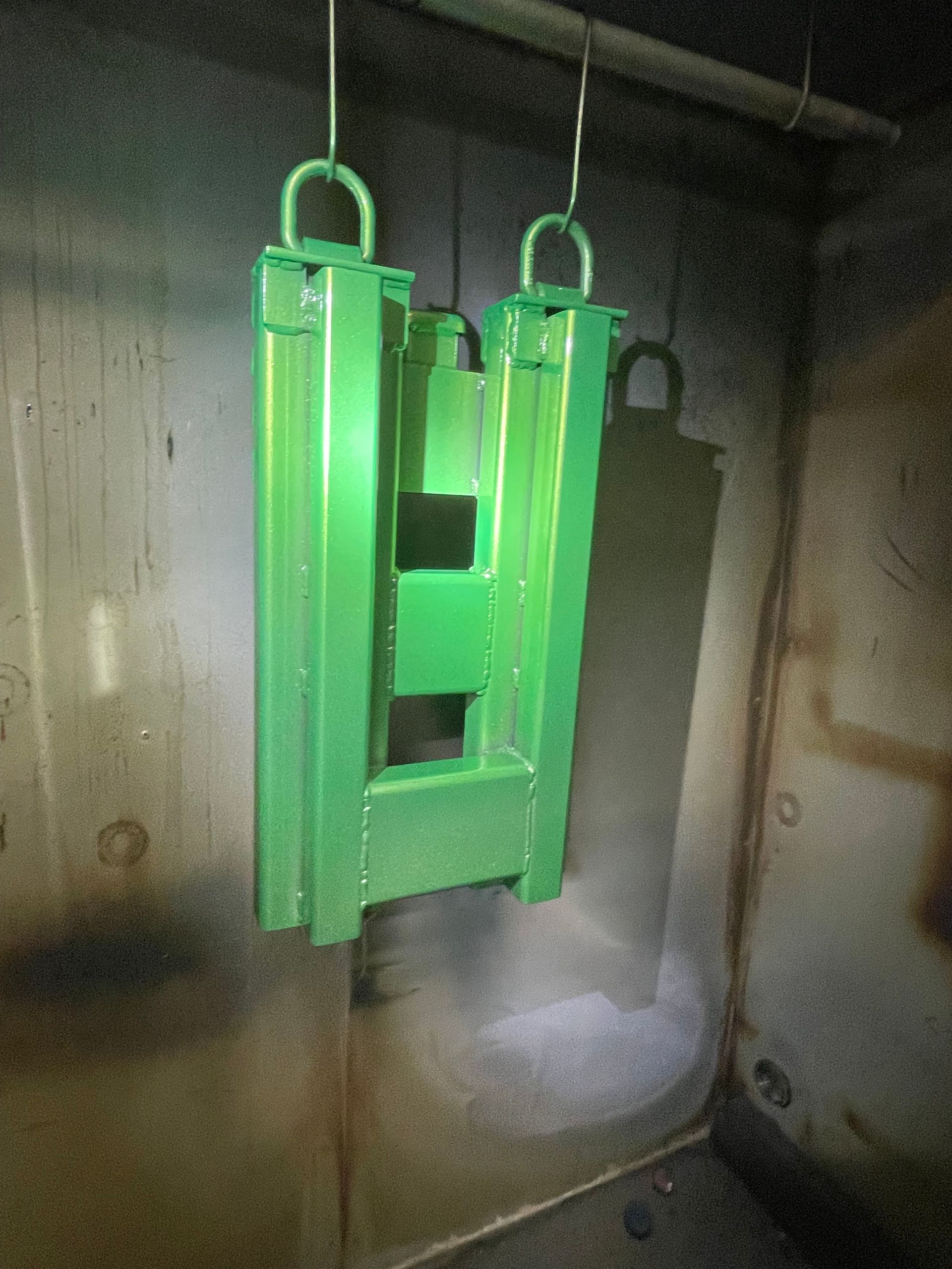 Green industrial metal fixture hanging in a dim concrete room