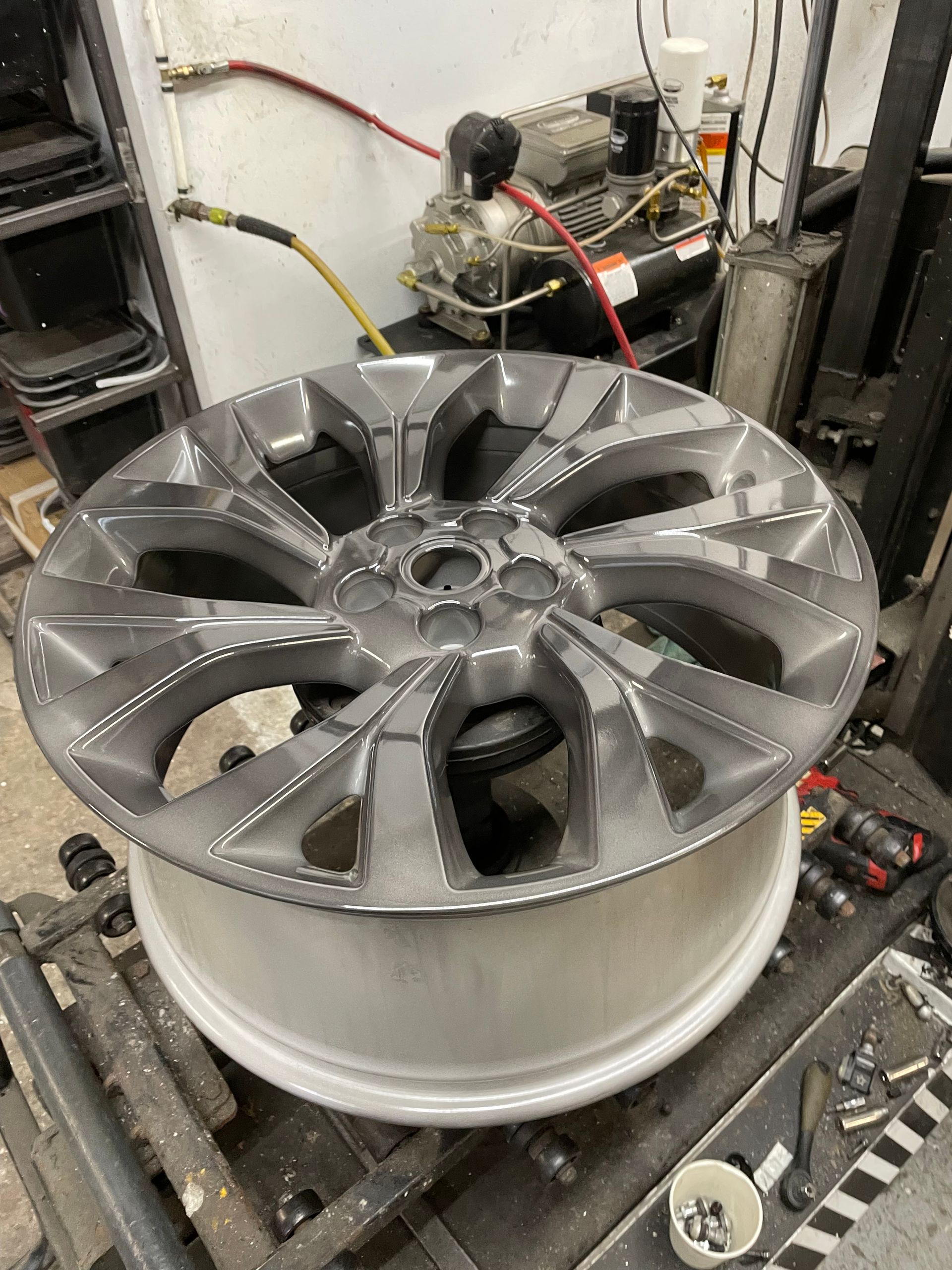Silver alloy car wheel rim on a machine in an industrial workshop