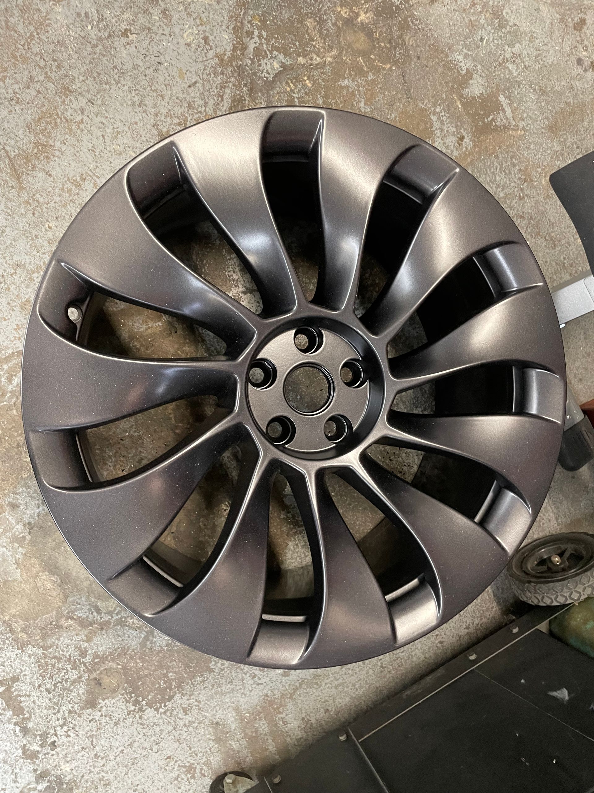 Black car wheel rim lying on a concrete floor.