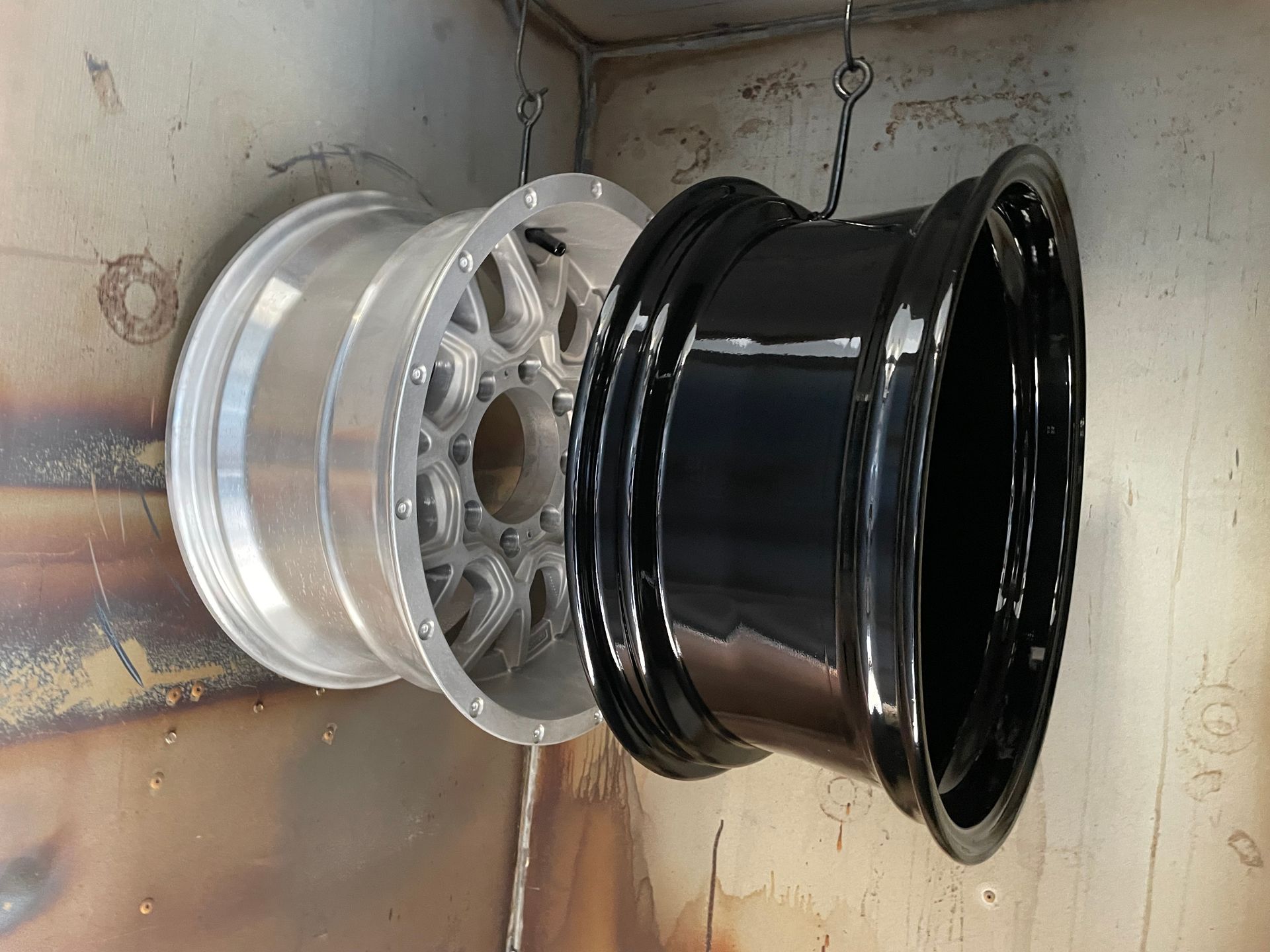 Two alloy car rims, one silver and one black, stacked inside a cardboard box
