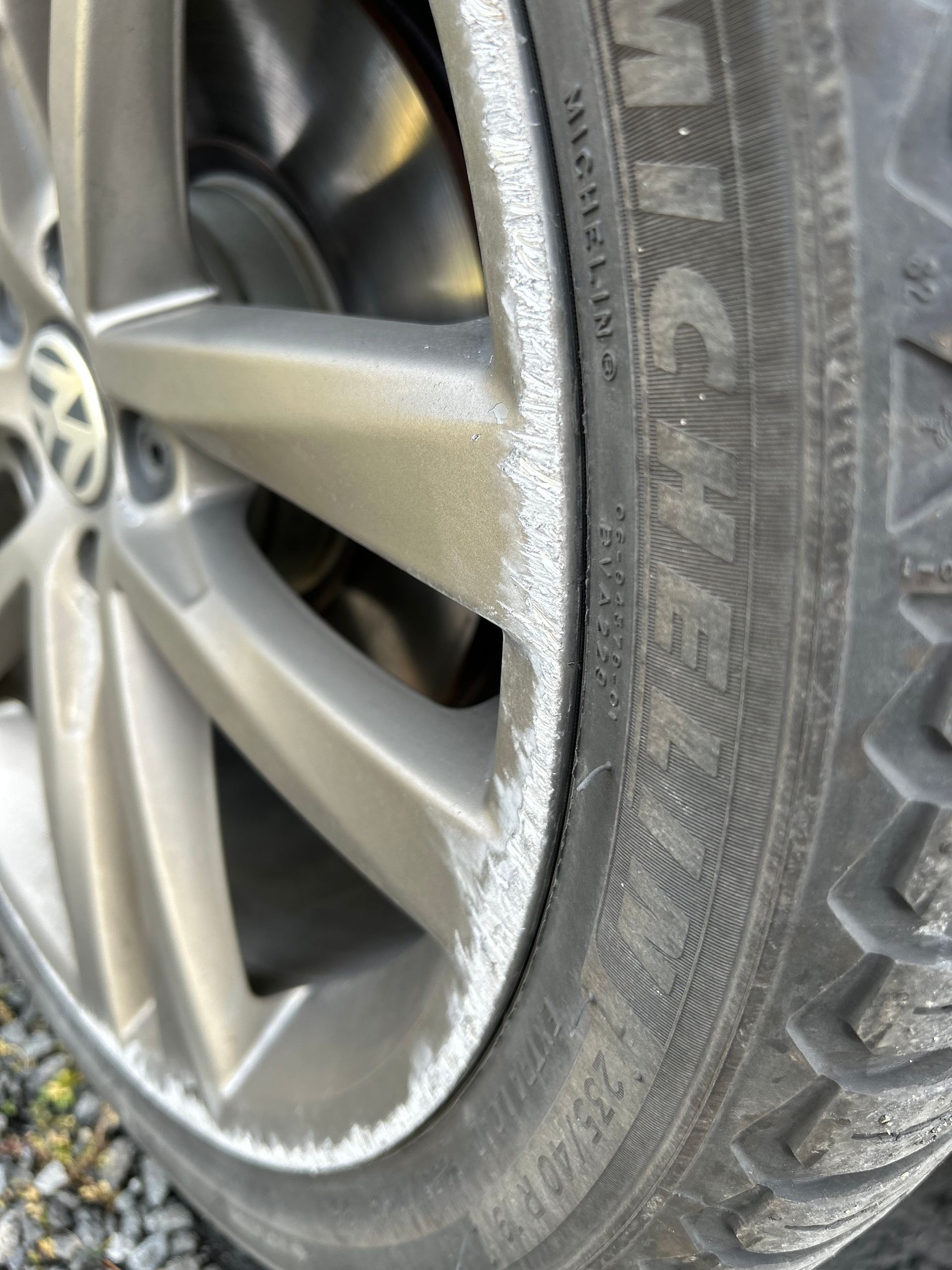 Close-up of a car wheel and tire with white scuff marks on the rim and sidewall